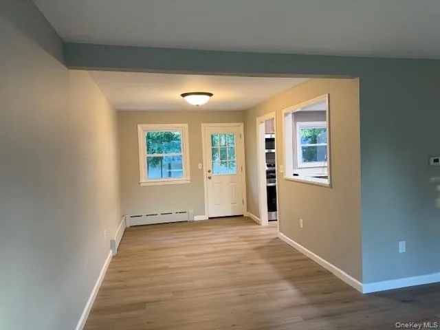 Doorway featuring a baseboard heating unit and wood finished floors Doorway featuring a baseboard heating unit and wood finished floors