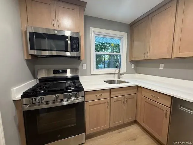 Kitchen featuring stainless steel appliances, light wood-style flooring, and light countertops. Kitchen featuring stainless steel appliances, light wood-style flooring, and light countertops.