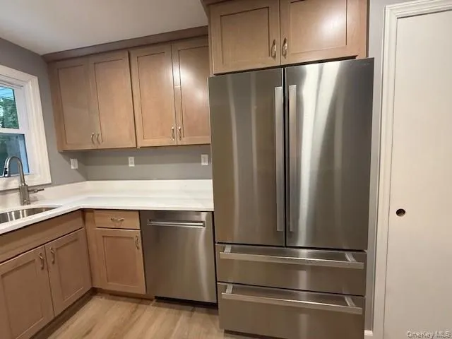 Kitchen with stainless steel appliances, light wood-type flooring, and light countertops Kitchen with stainless steel appliances, light wood-type flooring, and light countertops