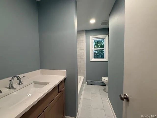 Full bath featuring a baseboard heating unit, marble finish floors, and vanity. Full bath featuring a baseboard heating unit, marble finish floors, and vanity.