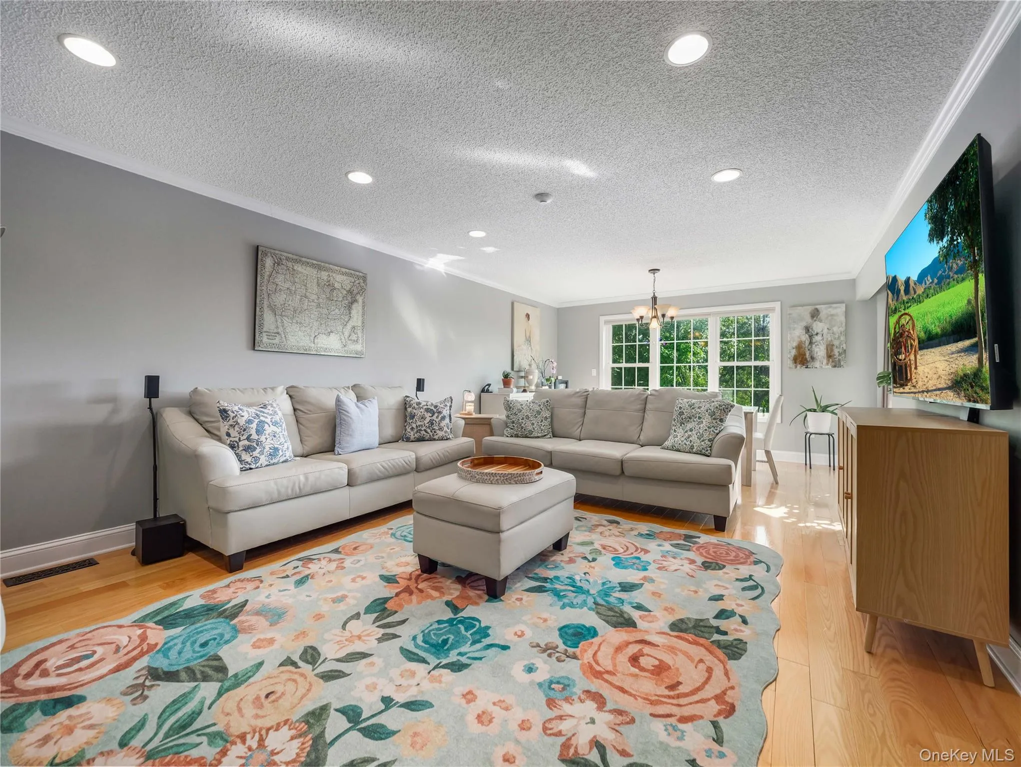 Living area featuring wood-finish flooring, recessed lighting, crown molding, and multi-pane grid windows Living area featuring wood-finish flooring, recessed lighting, crown molding, and multi-pane grid windows