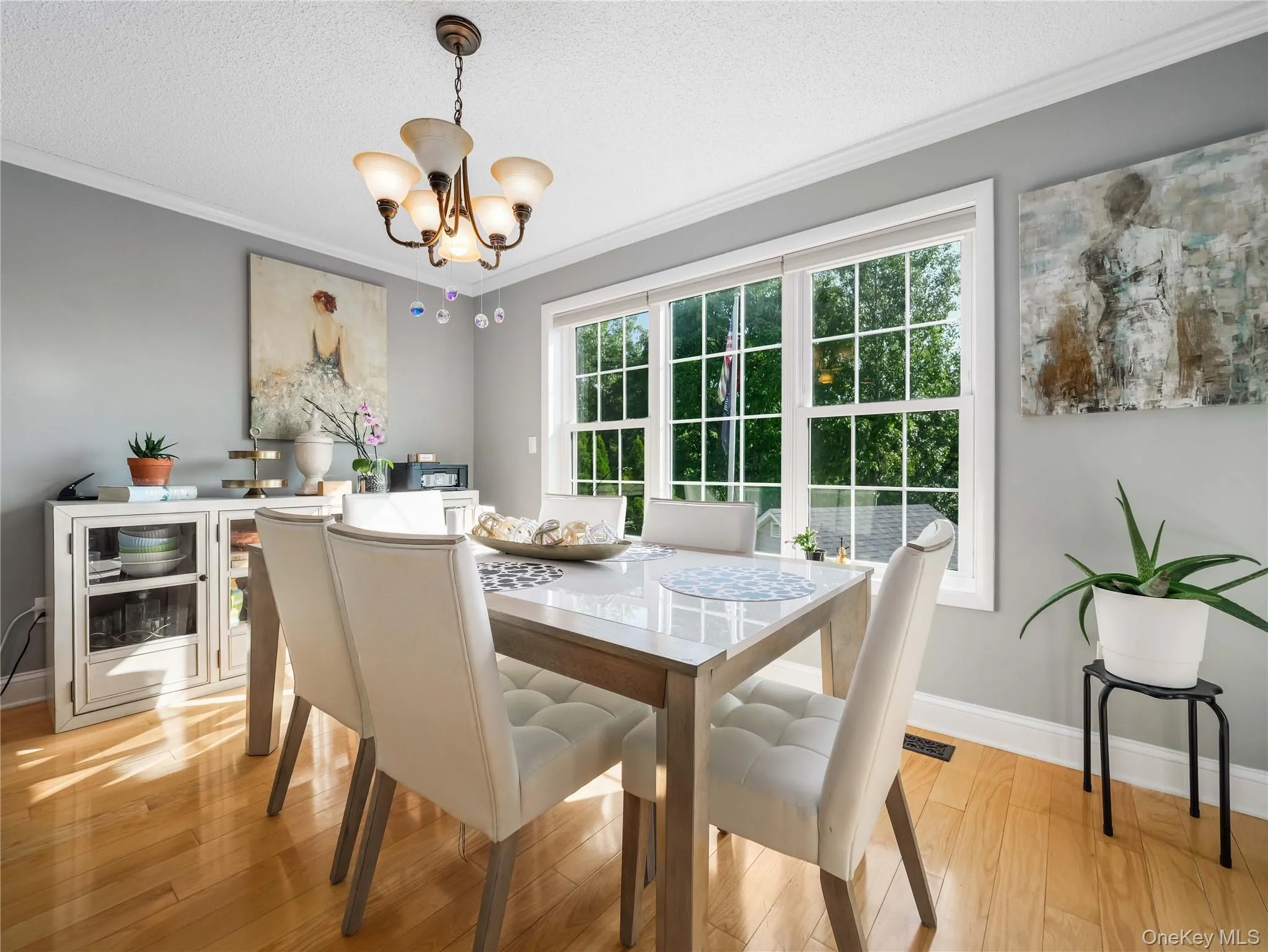 Dining room featuring wood-finish flooring, a multi-light chandelier, a built-in cabinetry unit, and a triple-pane window with muntins Dining room featuring wood-finish flooring, a multi-light chandelier, a built-in cabinetry unit, and a triple-pane window with muntins