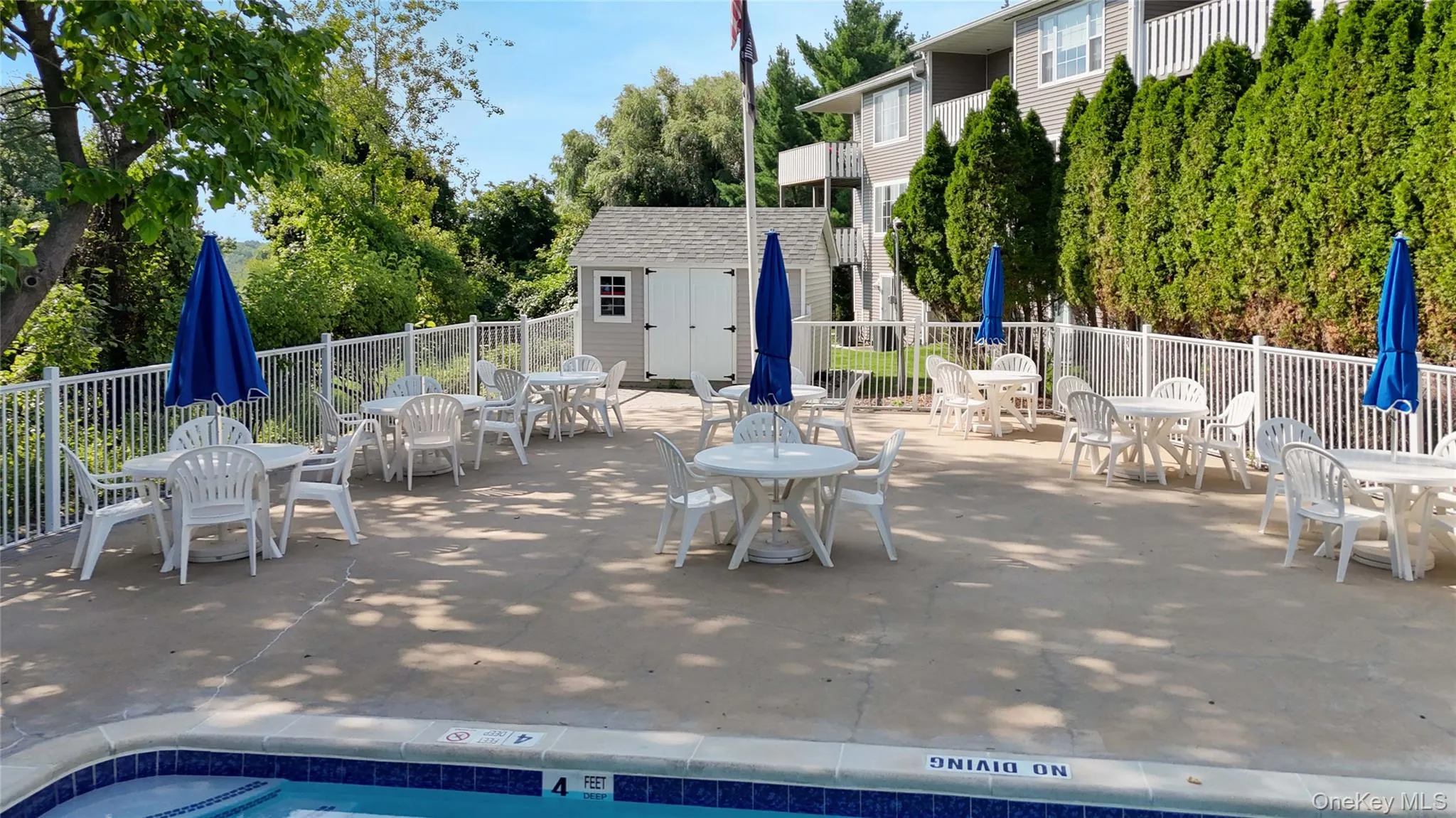 Outdoor pool area featuring a concrete patio, perimeter metal fencing, and a detached storage shed Outdoor pool area featuring a concrete patio, perimeter metal fencing, and a detached storage shed