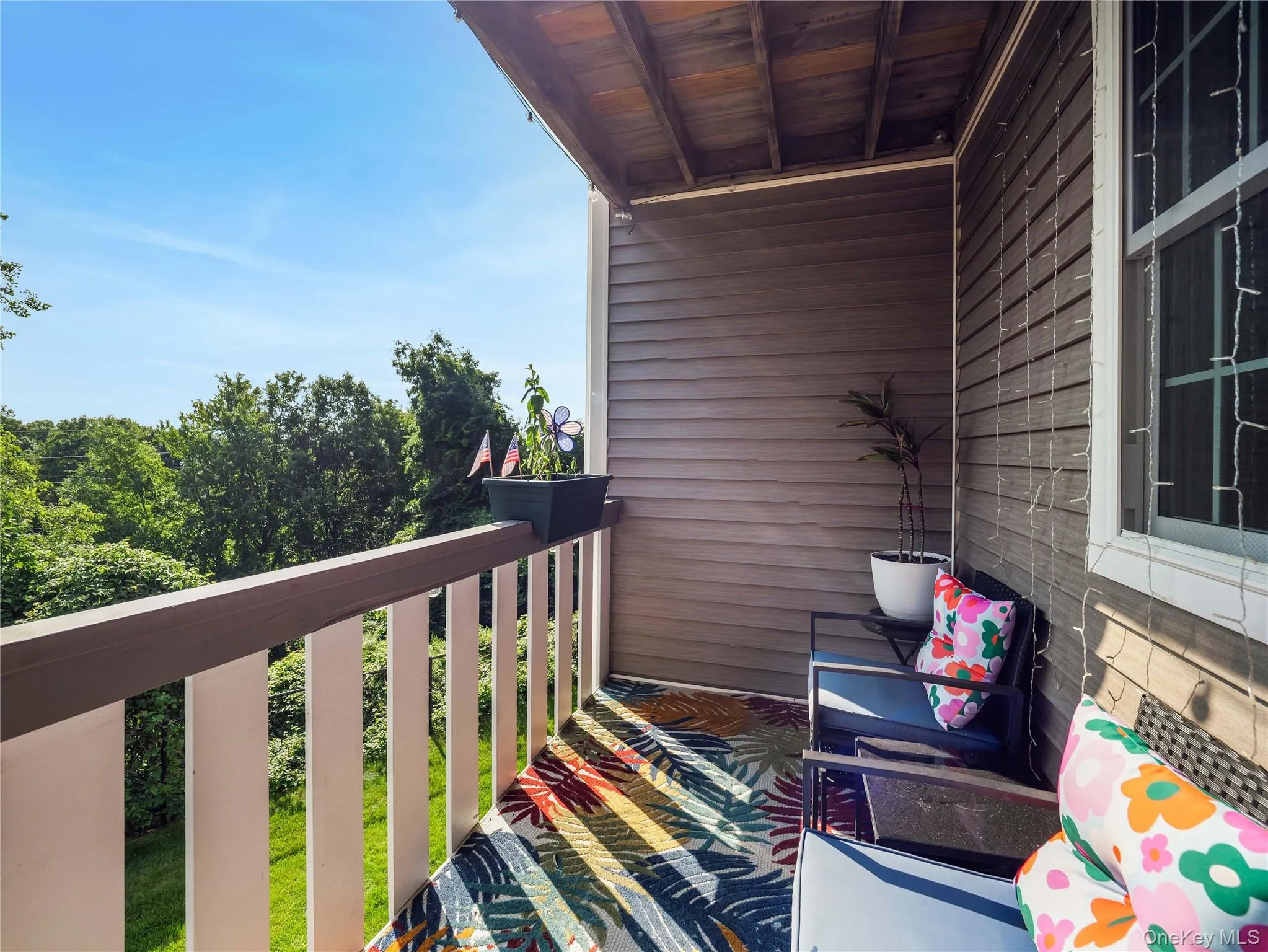 Covered balcony featuring horizontal lap siding, a wooden top rail, and vertical balusters Covered balcony featuring horizontal lap siding, a wooden top rail, and vertical balusters