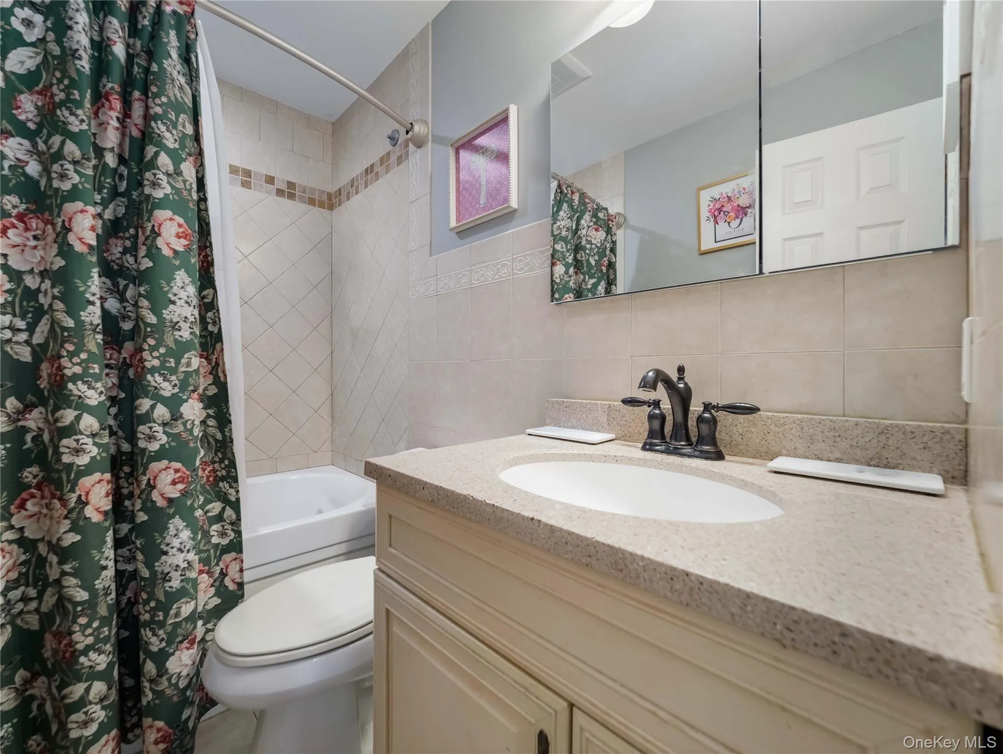 Vanity cabinet with a stone-composite countertop, undermount sink, oil-rubbed bronze faucet, wall-mounted medicine cabinet, and tiled shower-tub surround Vanity cabinet with a stone-composite countertop, undermount sink, oil-rubbed bronze faucet, wall-mounted medicine cabinet, and tiled shower-tub surround