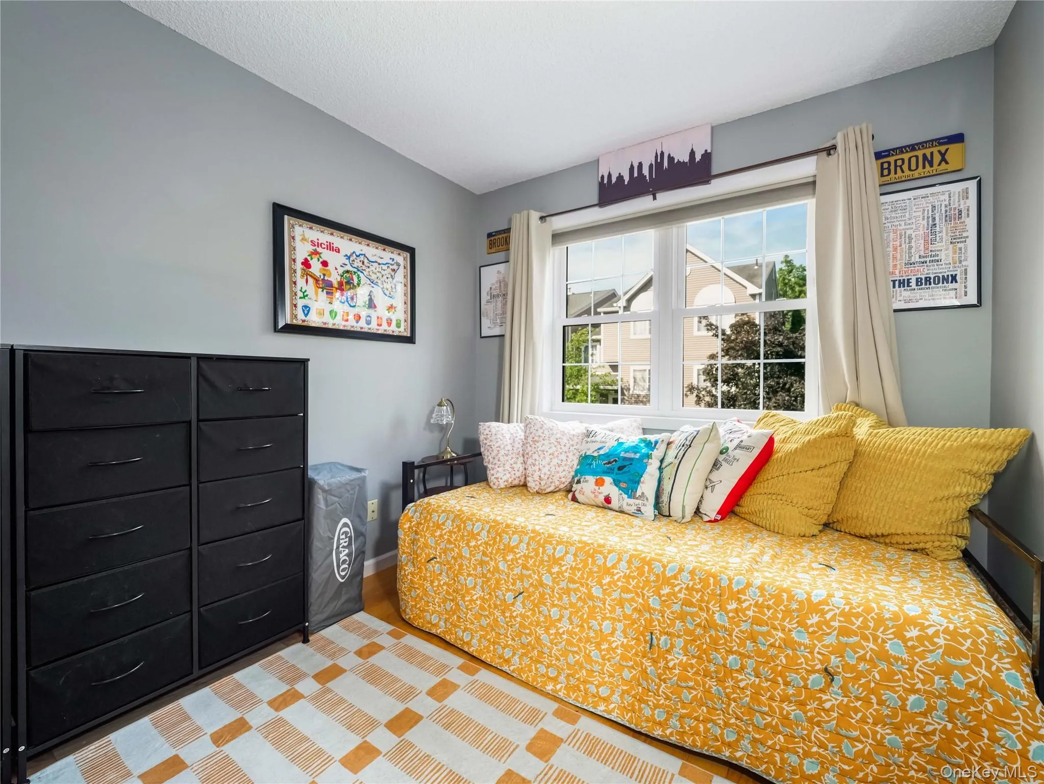 Room featuring light grey wall paint, wood-finish flooring, and a multi-pane window Room featuring light grey wall paint, wood-finish flooring, and a multi-pane window
