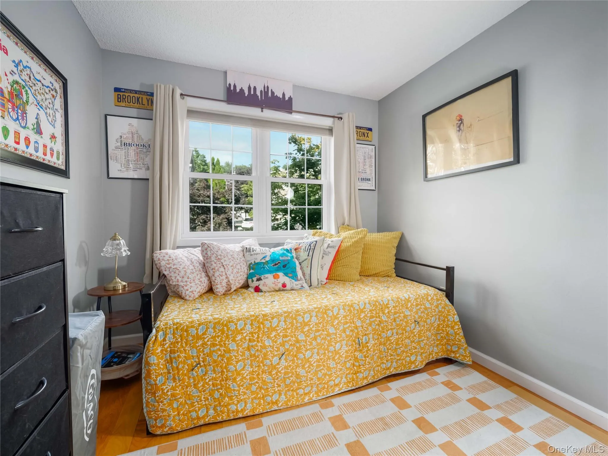 Room featuring wood-finish flooring, dual-pane windows with muntin detail, and neutral wall paint Room featuring wood-finish flooring, dual-pane windows with muntin detail, and neutral wall paint