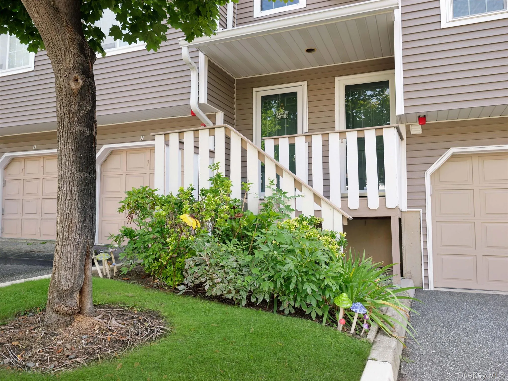Exterior featuring vinyl siding, recessed entryway, attached garage bays, and a wood staircase with balustrades Exterior featuring vinyl siding, recessed entryway, attached garage bays, and a wood staircase with balustrades