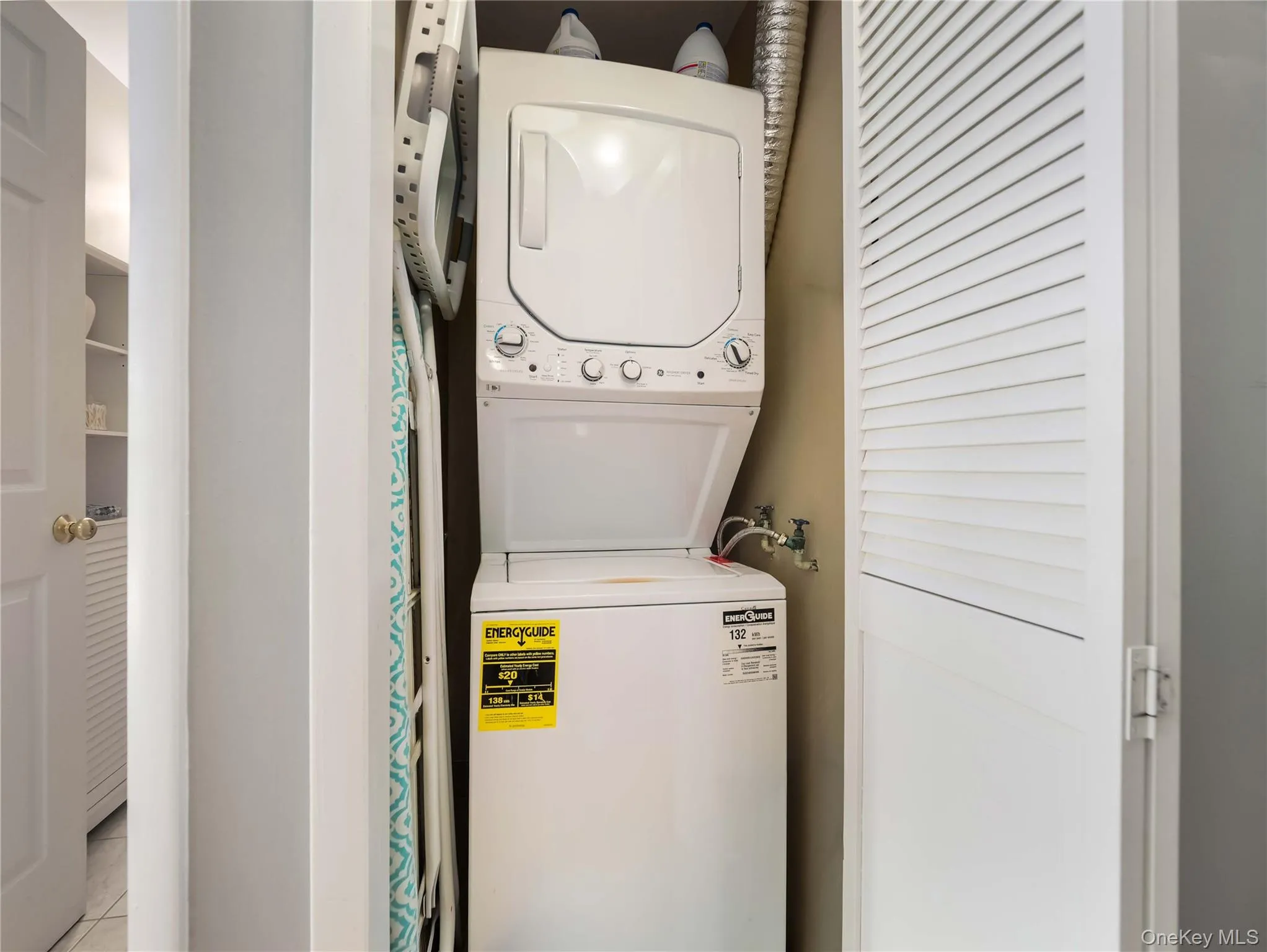 Stacked white laundry unit enclosed by louvered bi-fold doors Stacked white laundry unit enclosed by louvered bi-fold doors