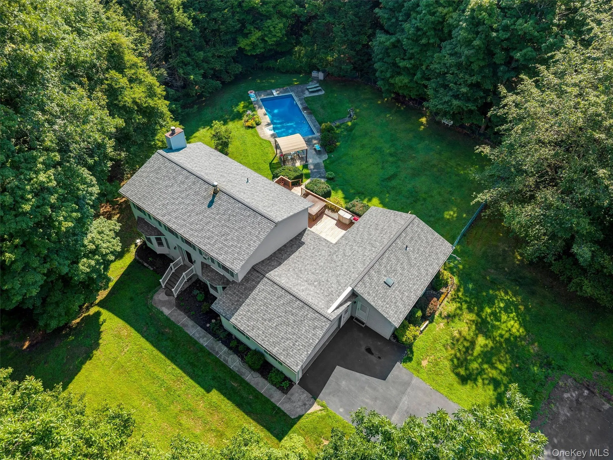 Expansive property featuring a multi-level structure, paved driveway, mature trees, a swimming pool, and a dedicated patio area Expansive property featuring a multi-level structure, paved driveway, mature trees, a swimming pool, and a dedicated patio area