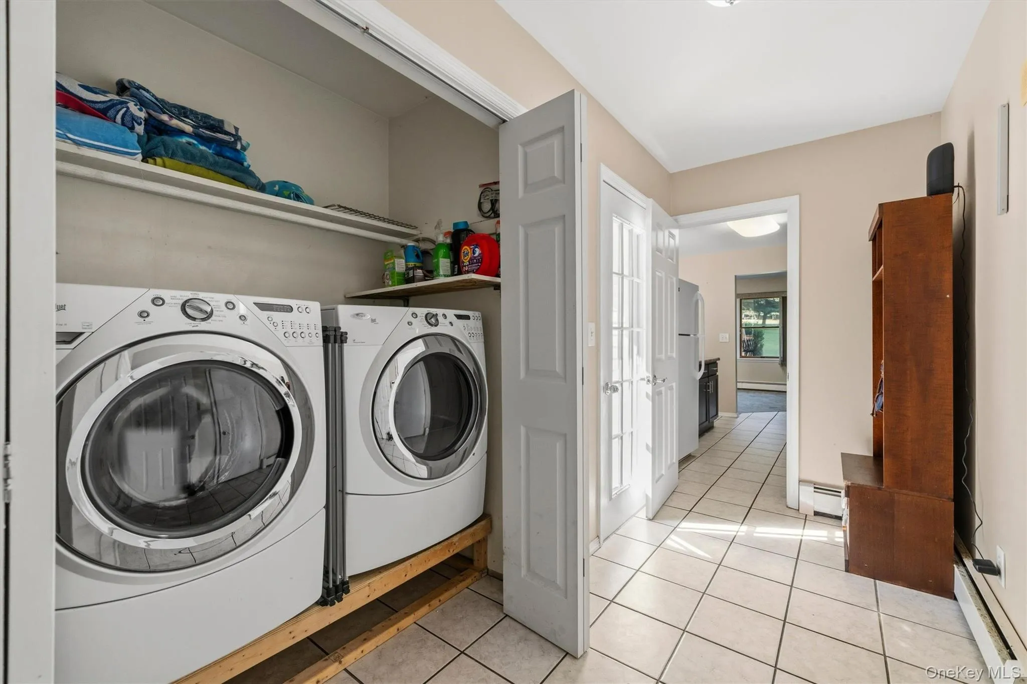 Laundry area with stacked appliances and shelving Laundry area with stacked appliances and shelving