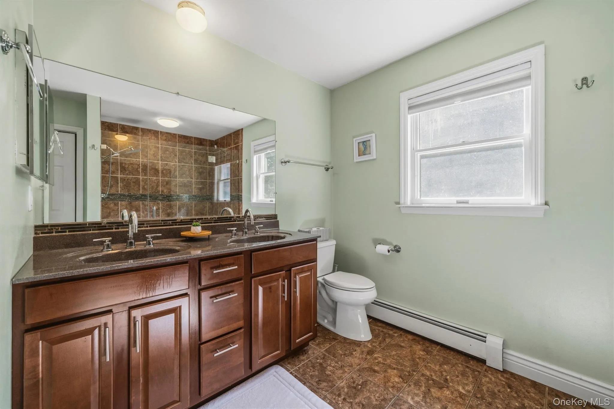 Double vanity with dark wood-finish cabinetry, integrated sinks, and a large wall-mounted mirror Double vanity with dark wood-finish cabinetry, integrated sinks, and a large wall-mounted mirror