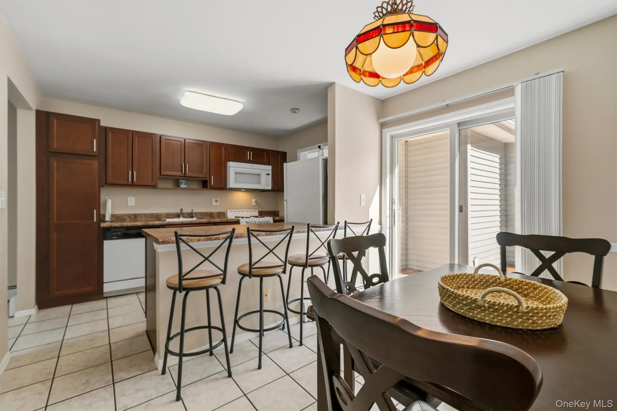 Mother/daughter Kitchen featuring wood-finish cabinetry, white appliances, a breakfast bar, and tile flooring Mother/daughter Kitchen featuring wood-finish cabinetry, white appliances, a breakfast bar, and tile flooring