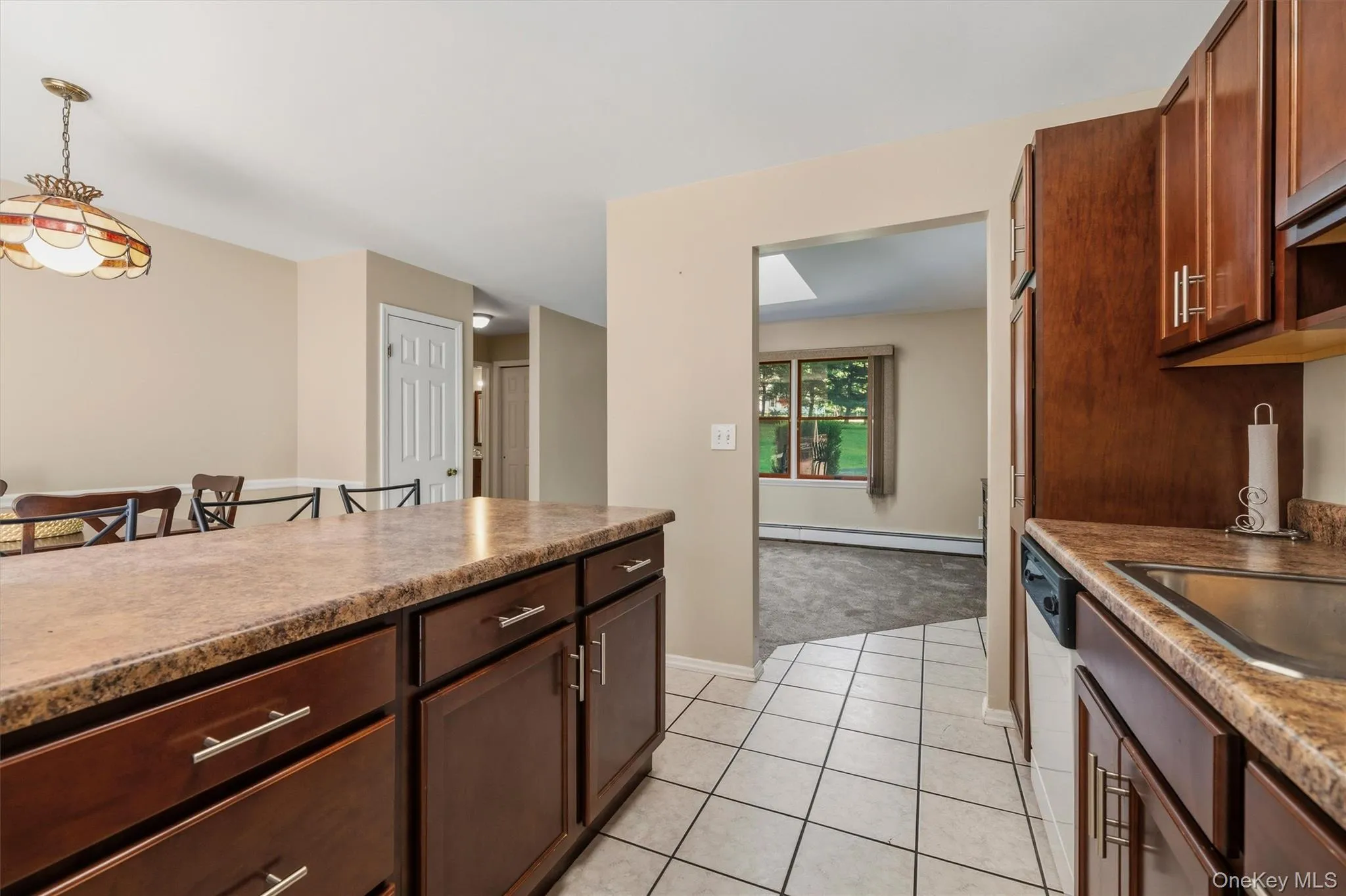 Mother/daughter Kitchen featuring dark wood-finish cabinetry, light-toned countertops, and tile flooring Mother/daughter Kitchen featuring dark wood-finish cabinetry, light-toned countertops, and tile flooring