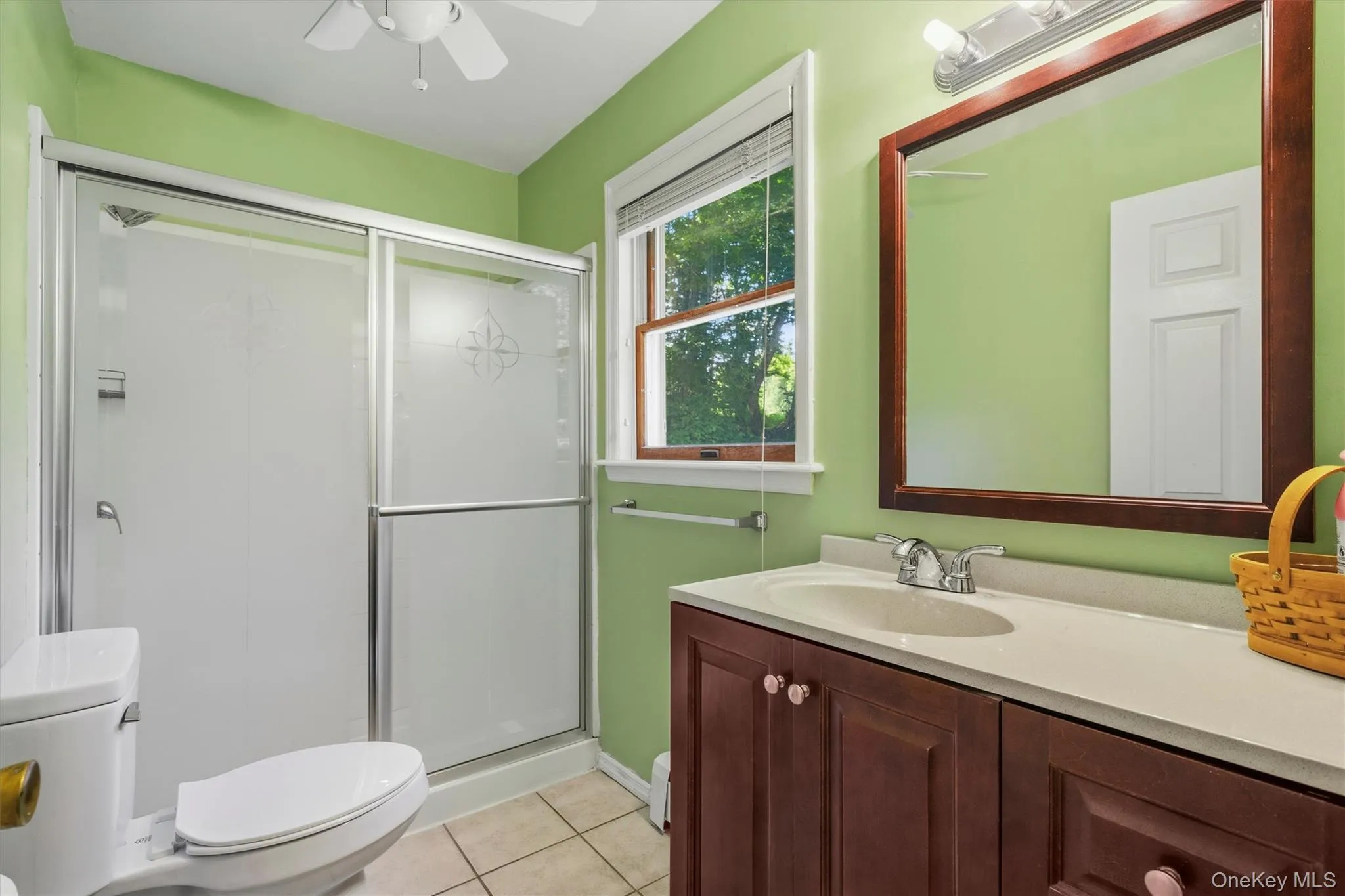 Mother / daughter Bathroom - Sliding glass shower enclosure, wood-finish vanity with countertop, framed mirror, and ceiling fan Mother / daughter Bathroom - Sliding glass shower enclosure, wood-finish vanity with countertop, framed mirror, and ceiling fan