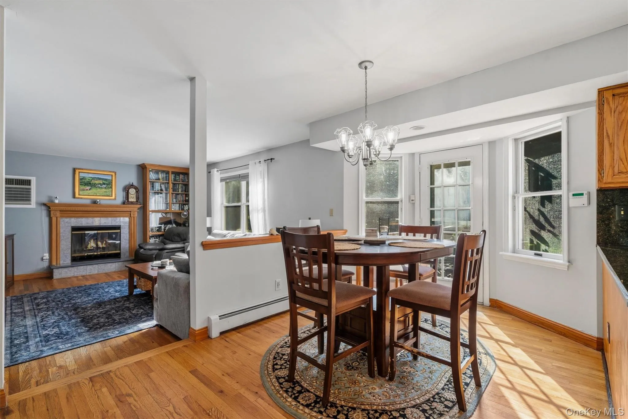 Hardwood flooring, a fireplace with a wood mantel, a built-in bookcase, a chandelier, and a bay window Hardwood flooring, a fireplace with a wood mantel, a built-in bookcase, a chandelier, and a bay window