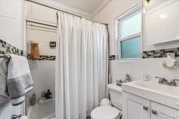 The second floor bathroom is clean and bright, featuring a white vanity, matching wall tiles, and a stylish mosaic border. A frosted window lets in great natural light while keeping the space private. The second floor bathroom is clean and bright, featuring a white vanity, matching wall tiles, and a stylish mosaic border. A frosted window lets in great natural light while keeping the space private.