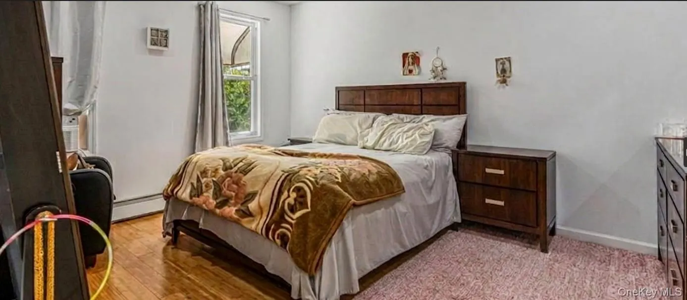 The spacious master bedroom features warm hardwood flooring, clean white walls, and a bright window that overlooks the property. The expansive layout easily accommodates a large king or queen bed set alongside matching nightstands and an oversized dresser The spacious master bedroom features warm hardwood flooring, clean white walls, and a bright window that overlooks the property. The expansive layout easily accommodates a large king or queen bed set alongside matching nightstands and an oversized dresser