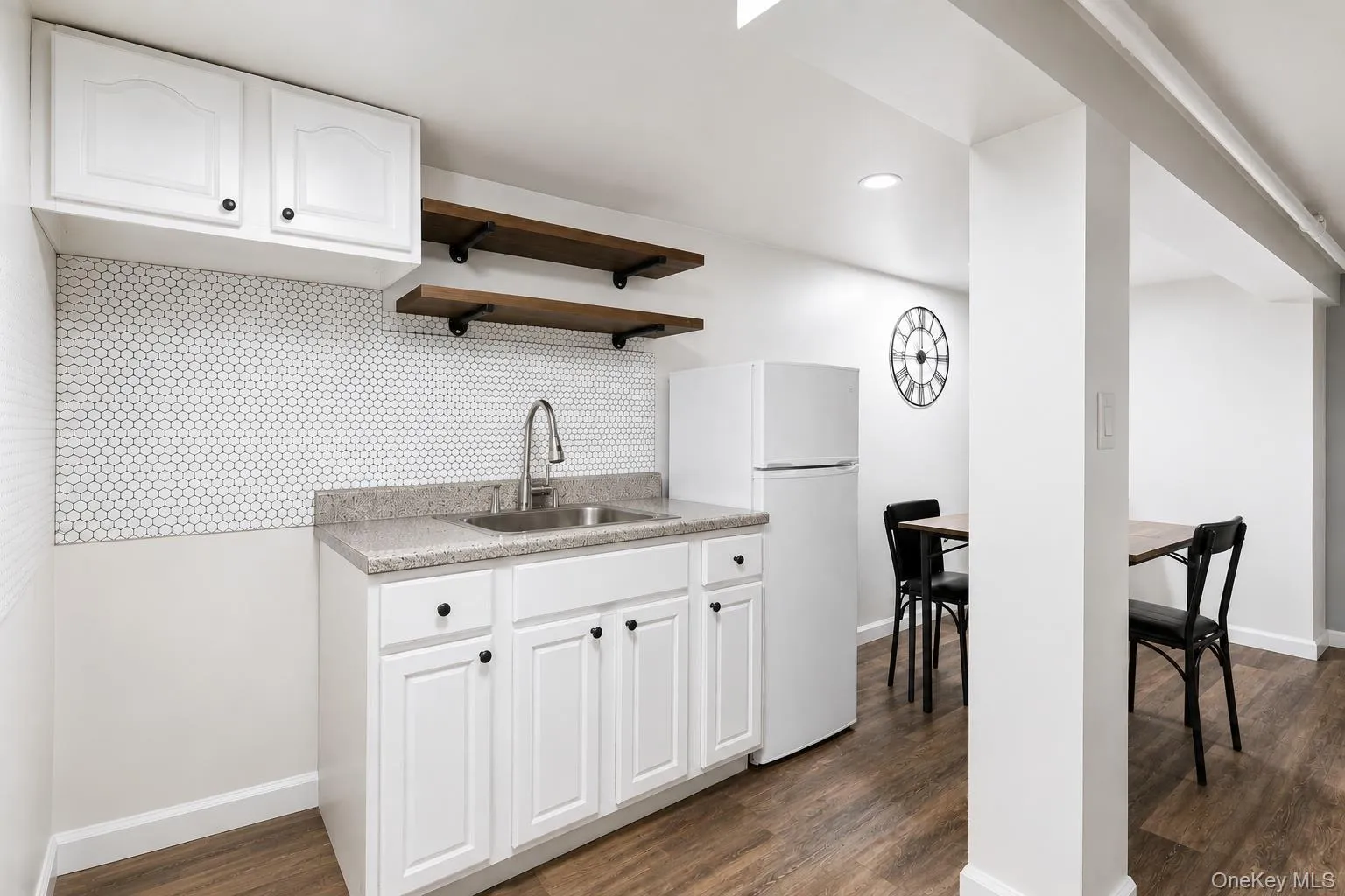 Cabinetry with black hardware, hexagon tile backsplash, wood-finish flooring. Cabinetry with black hardware, hexagon tile backsplash, wood-finish flooring.
