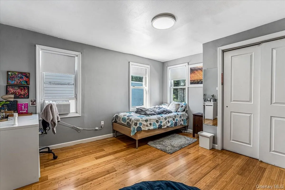 This very spacious second bedroom features rich hardwood floors, clean grey walls, and a large double-door closet. Multiple windows flood the room with natural light, offering plenty of space for a bed, desk, and extra furniture. This very spacious second bedroom features rich hardwood floors, clean grey walls, and a large double-door closet. Multiple windows flood the room with natural light, offering plenty of space for a bed, desk, and extra furniture.