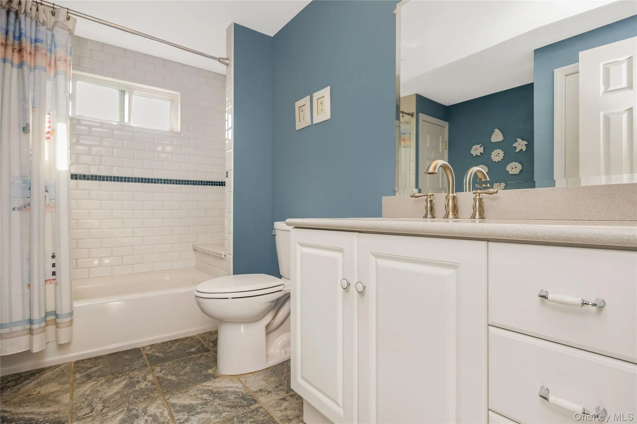 White subway tile shower surround with a decorative accent band, built-in tub, and a vanity with a light-colored countertop White subway tile shower surround with a decorative accent band, built-in tub, and a vanity with a light-colored countertop