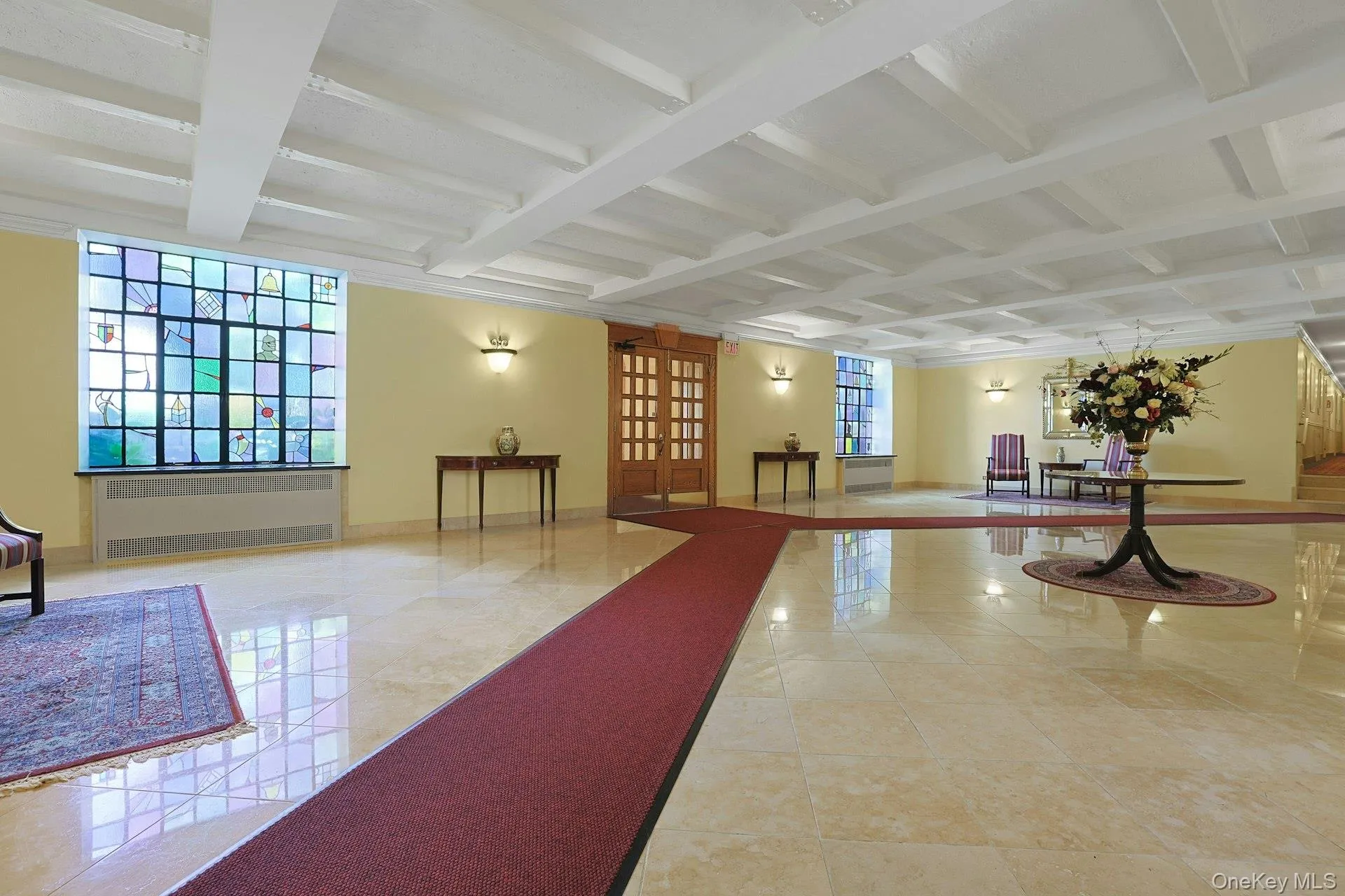 Coffered ceiling with recessed lighting, stained-glass window, light-toned polished tile flooring, and a paneled entry door Coffered ceiling with recessed lighting, stained-glass window, light-toned polished tile flooring, and a paneled entry door
