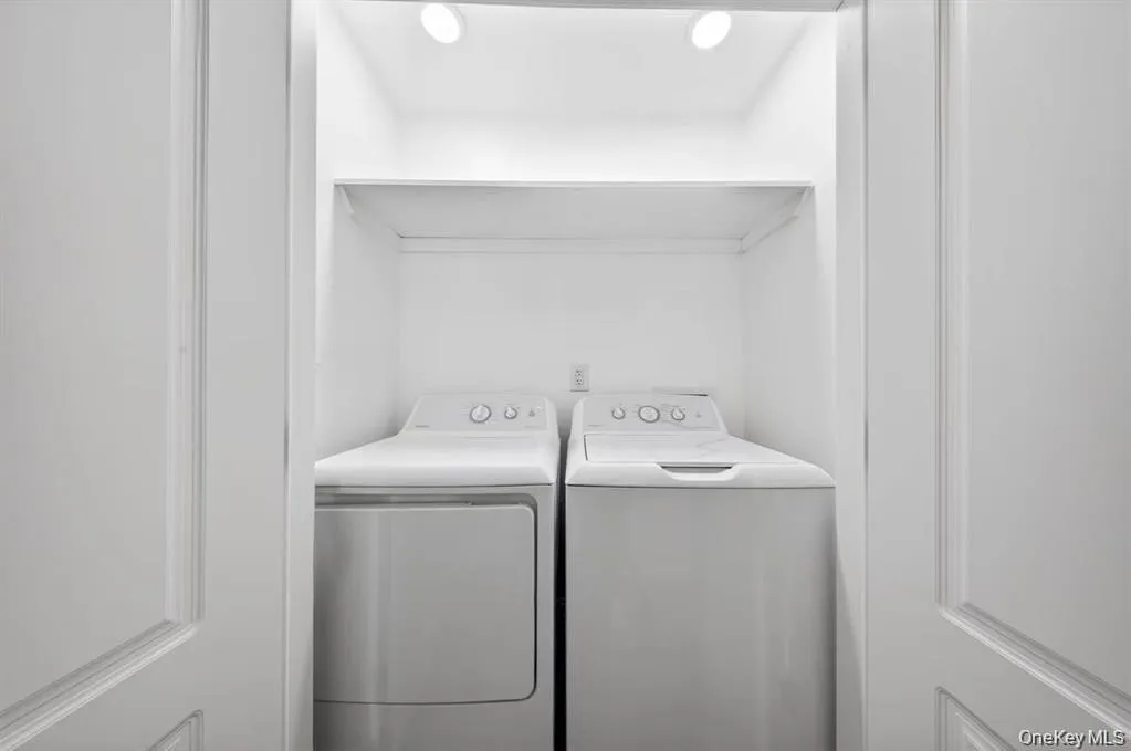 Laundry closet featuring built-in shelving, recessed lighting, and a white washer and dryer Laundry closet featuring built-in shelving, recessed lighting, and a white washer and dryer