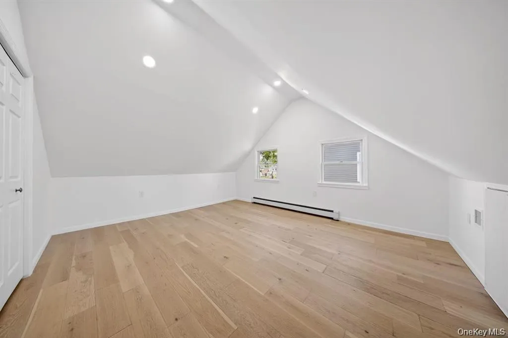Sloped ceiling room featuring recessed lighting, light wood-finish flooring, and white walls Sloped ceiling room featuring recessed lighting, light wood-finish flooring, and white walls