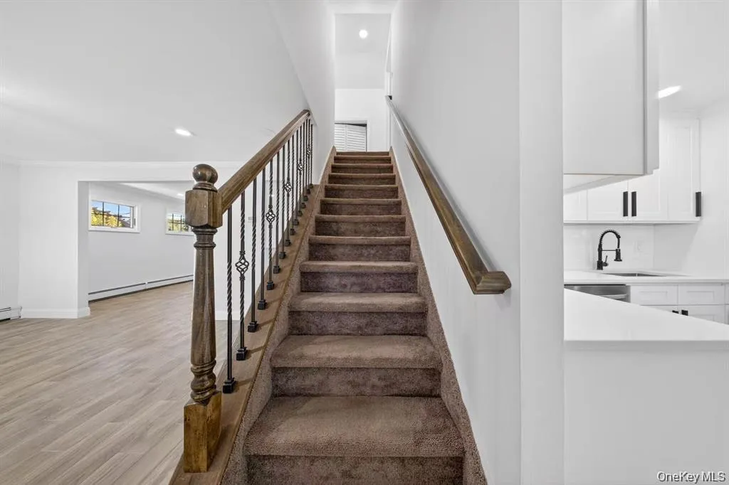 Carpeted staircase with wrought iron balusters and wood handrail Carpeted staircase with wrought iron balusters and wood handrail