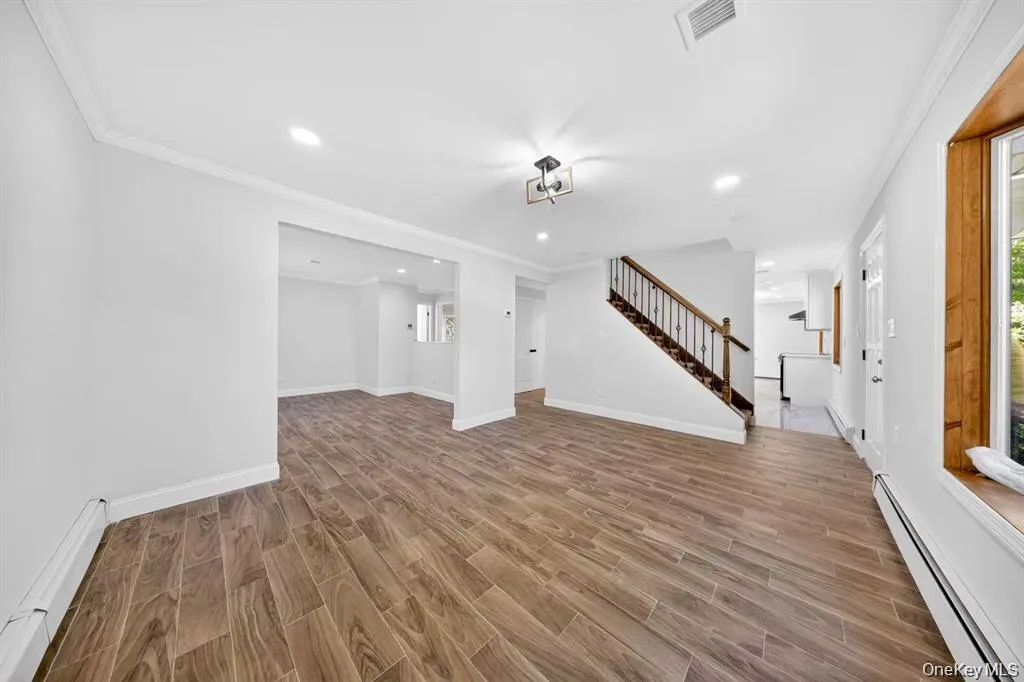 Wood-finish flooring throughout, recessed lighting, crown molding, and a wood-stained window frame Wood-finish flooring throughout, recessed lighting, crown molding, and a wood-stained window frame