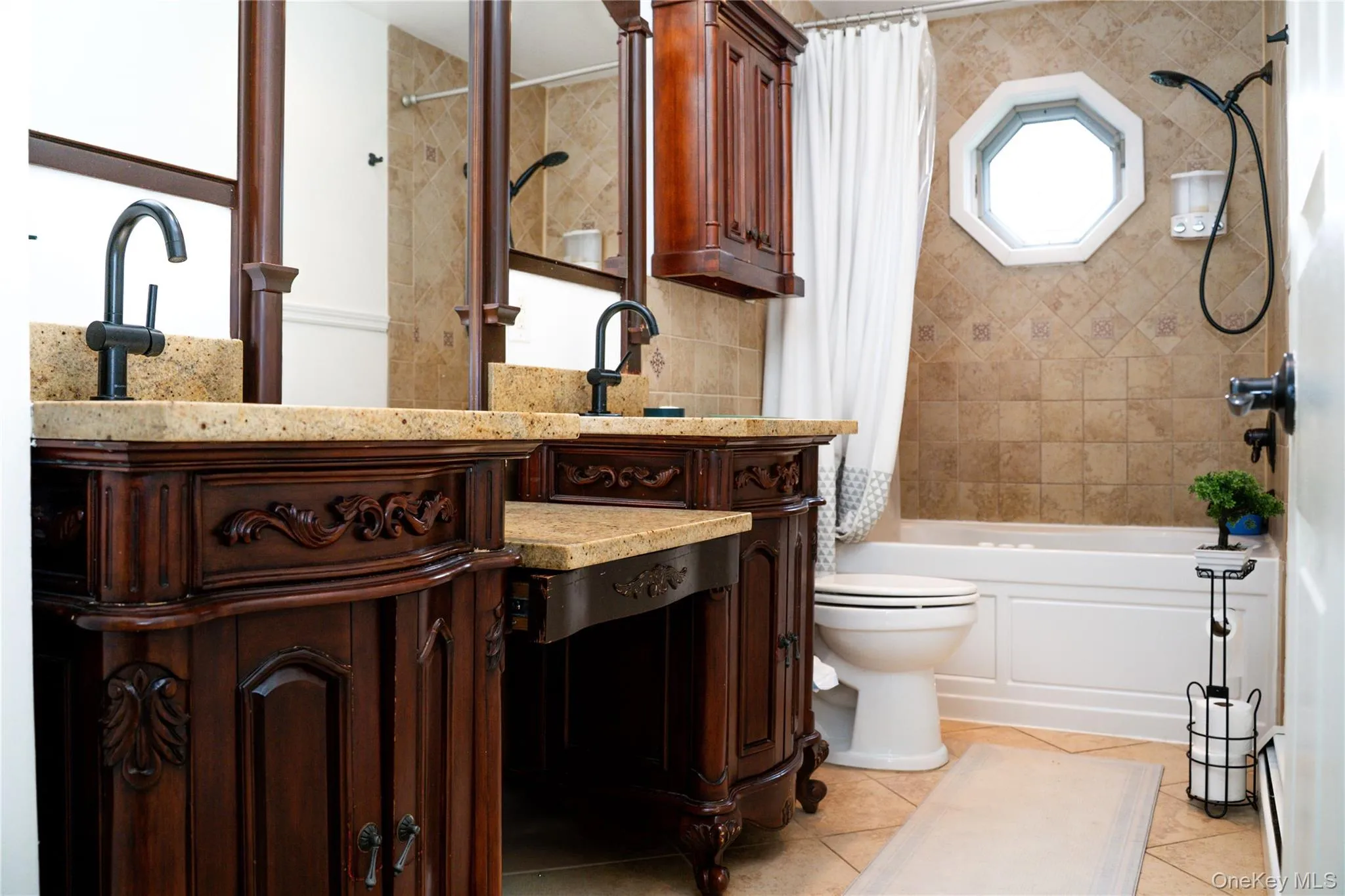 Elegant master bathroom featuring dual vanities with ornate wood cabinetry, marble countertops, and matte black faucetry Elegant master bathroom featuring dual vanities with ornate wood cabinetry, marble countertops, and matte black faucetry