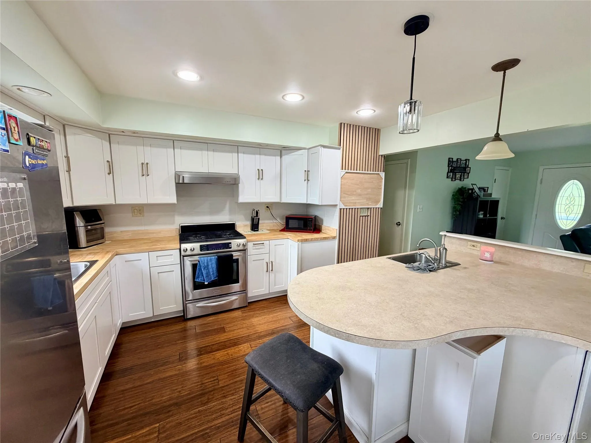 U-shaped kitchen featuring white cabinetry, light wood-finish countertops, stainless steel appliances, and wood-finish flooring U-shaped kitchen featuring white cabinetry, light wood-finish countertops, stainless steel appliances, and wood-finish flooring