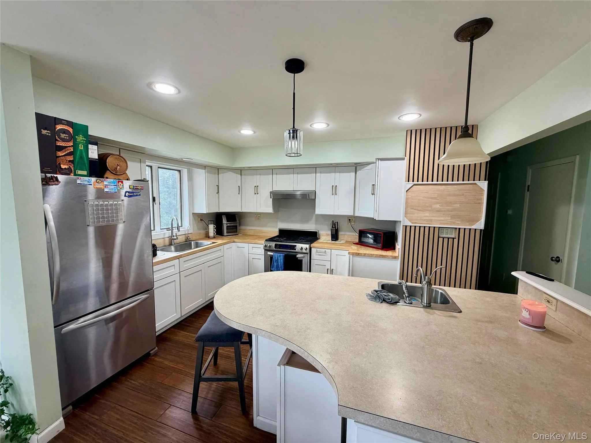 Modern kitchen featuring stainless steel appliances, white cabinetry, and a spacious light-finish island with seating Modern kitchen featuring stainless steel appliances, white cabinetry, and a spacious light-finish island with seating
