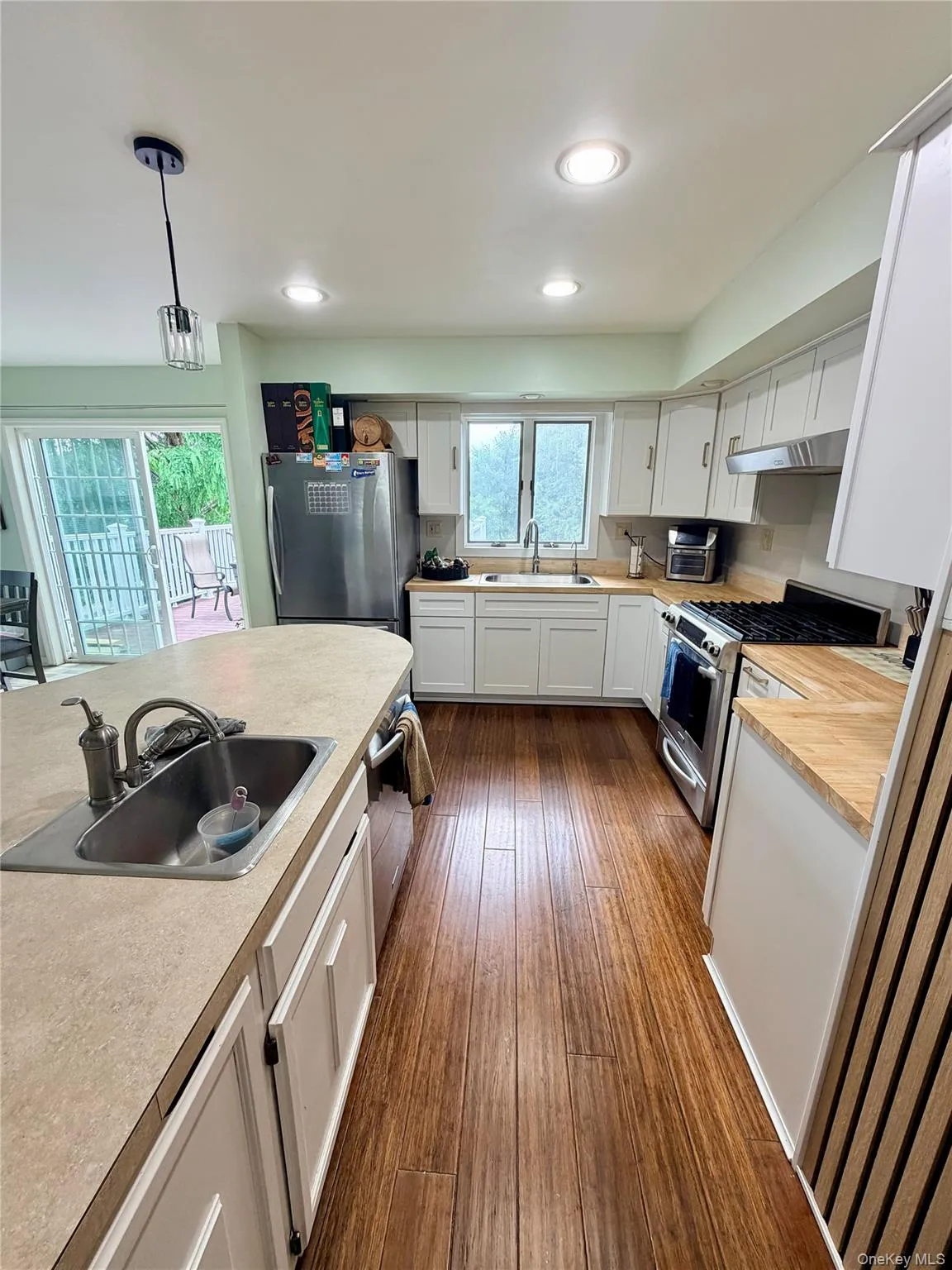 Kitchen featuring white cabinetry, stainless steel appliances, wood-finish flooring, and recessed lighting Kitchen featuring white cabinetry, stainless steel appliances, wood-finish flooring, and recessed lighting