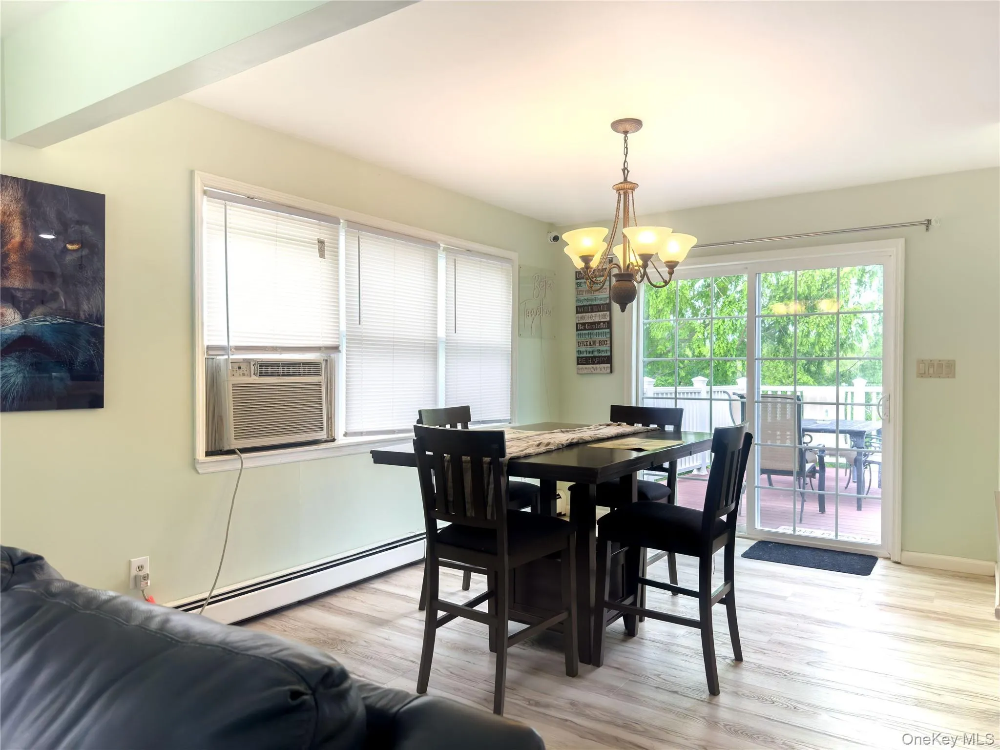 Bright dining area with wood-finish flooring, black dining table with seating for four, and a brass pendant light fixture Bright dining area with wood-finish flooring, black dining table with seating for four, and a brass pendant light fixture