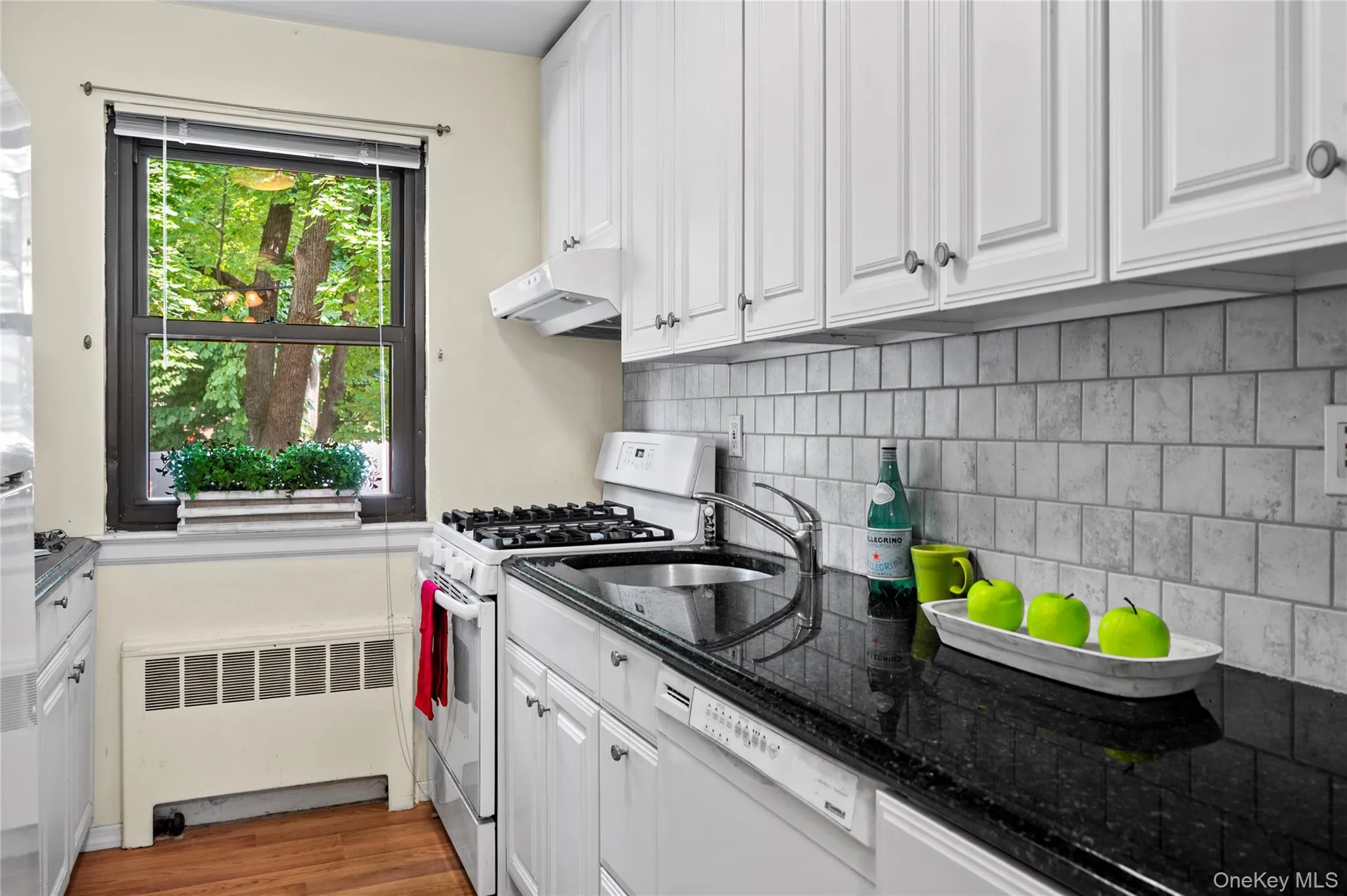 Kitchen featuring white paneled cabinetry, granite countertops, and a tiled backsplash Kitchen featuring white paneled cabinetry, granite countertops, and a tiled backsplash