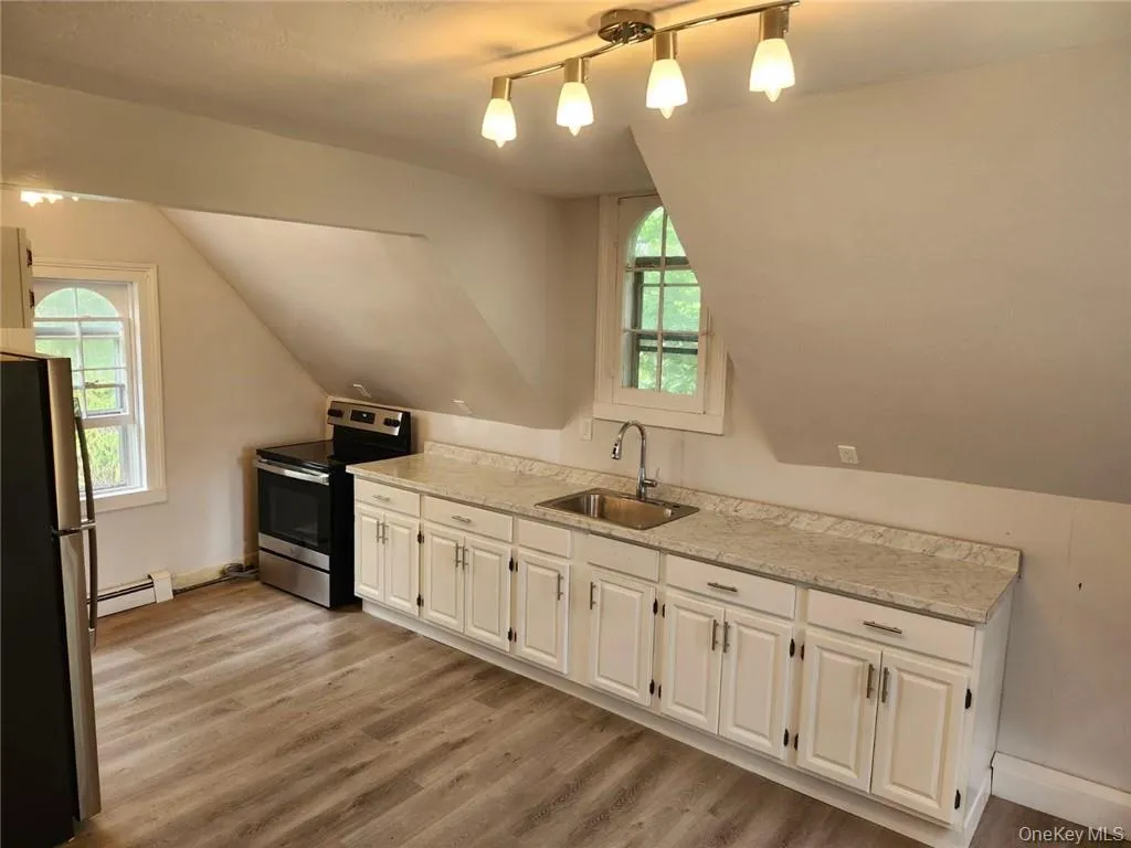 Kitchen with white cabinetry, Deep sink, light hardwood / wood-style floors, appliances with stainless steel finishes, and a wealth of natural light Kitchen with white cabinetry, Deep sink, light hardwood / wood-style floors, appliances with stainless steel finishes, and a wealth of natural light