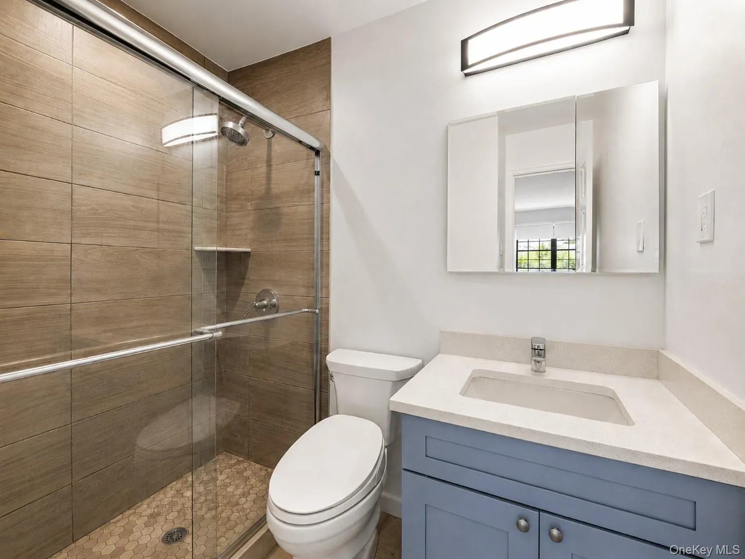 Walk-in shower with natural-toned tile surround and pebble-finish floor Walk-in shower with natural-toned tile surround and pebble-finish floor