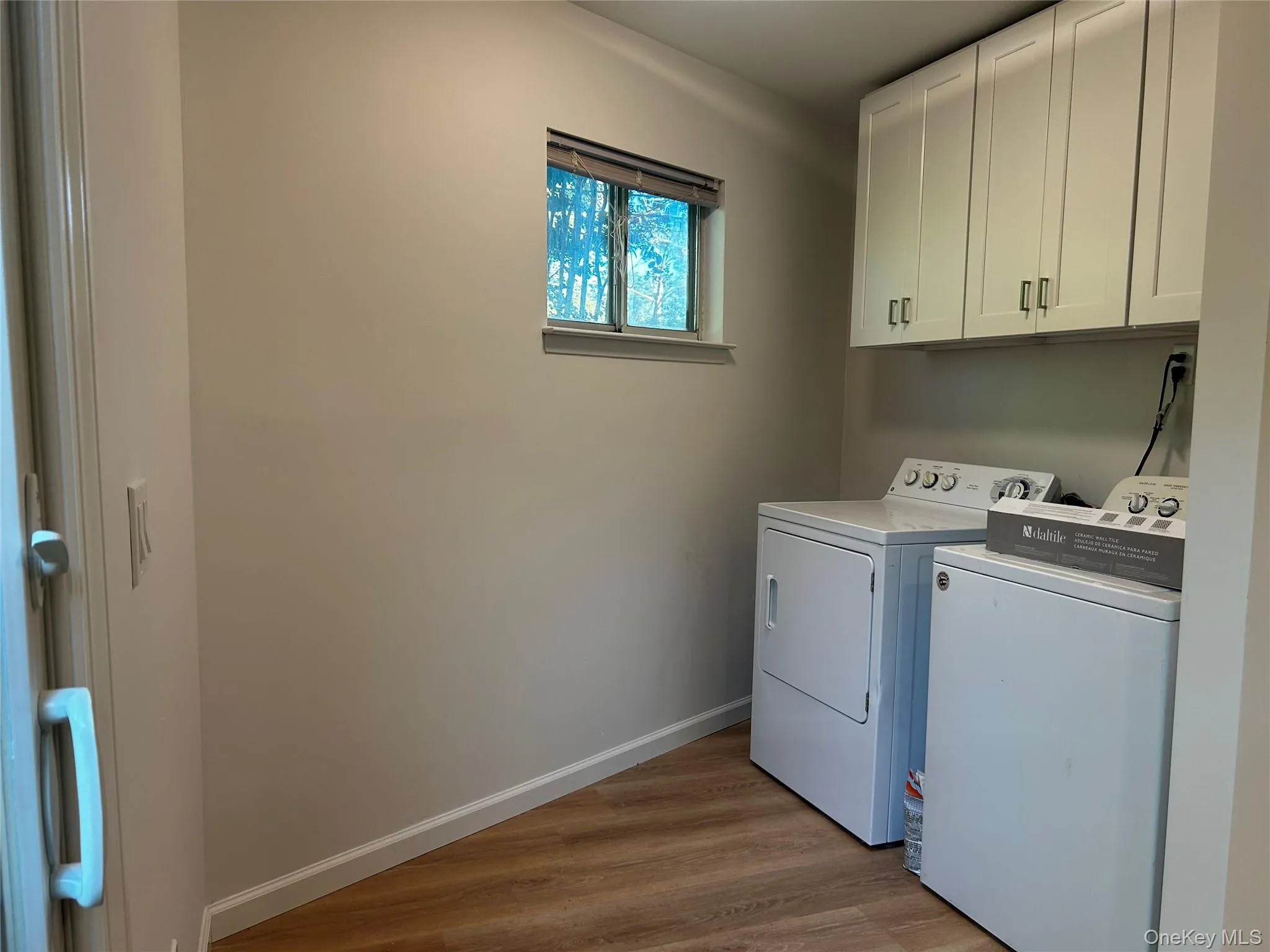Laundry area with luxury vinyl flooring, white cabinetry for storage, and a window. Additional space for storage if needed Laundry area with luxury vinyl flooring, white cabinetry for storage, and a window. Additional space for storage if needed