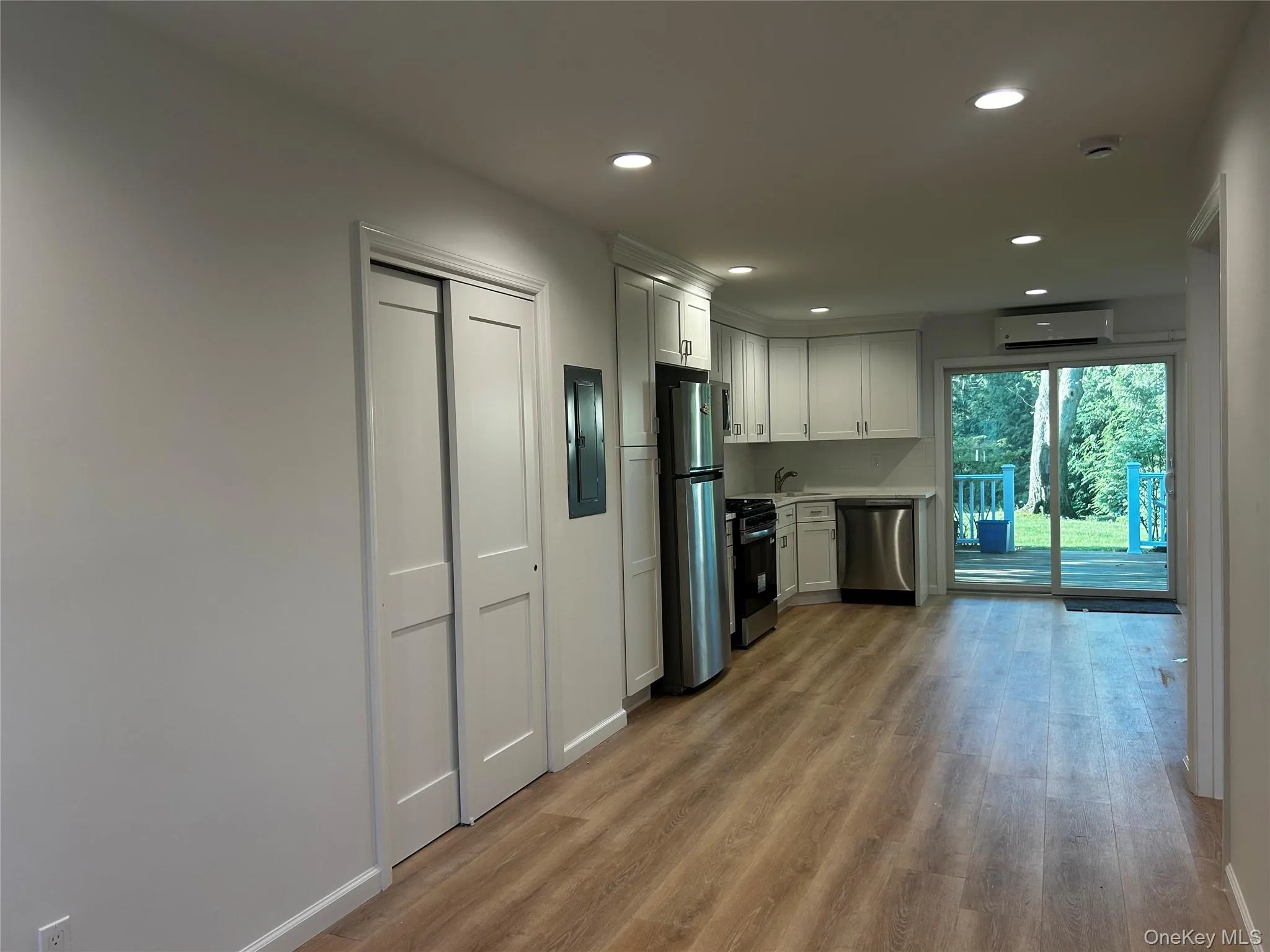 Open-concept living space featuring luxury vinyl flooring, recessed lighting, and white cabinetry Open-concept living space featuring luxury vinyl flooring, recessed lighting, and white cabinetry