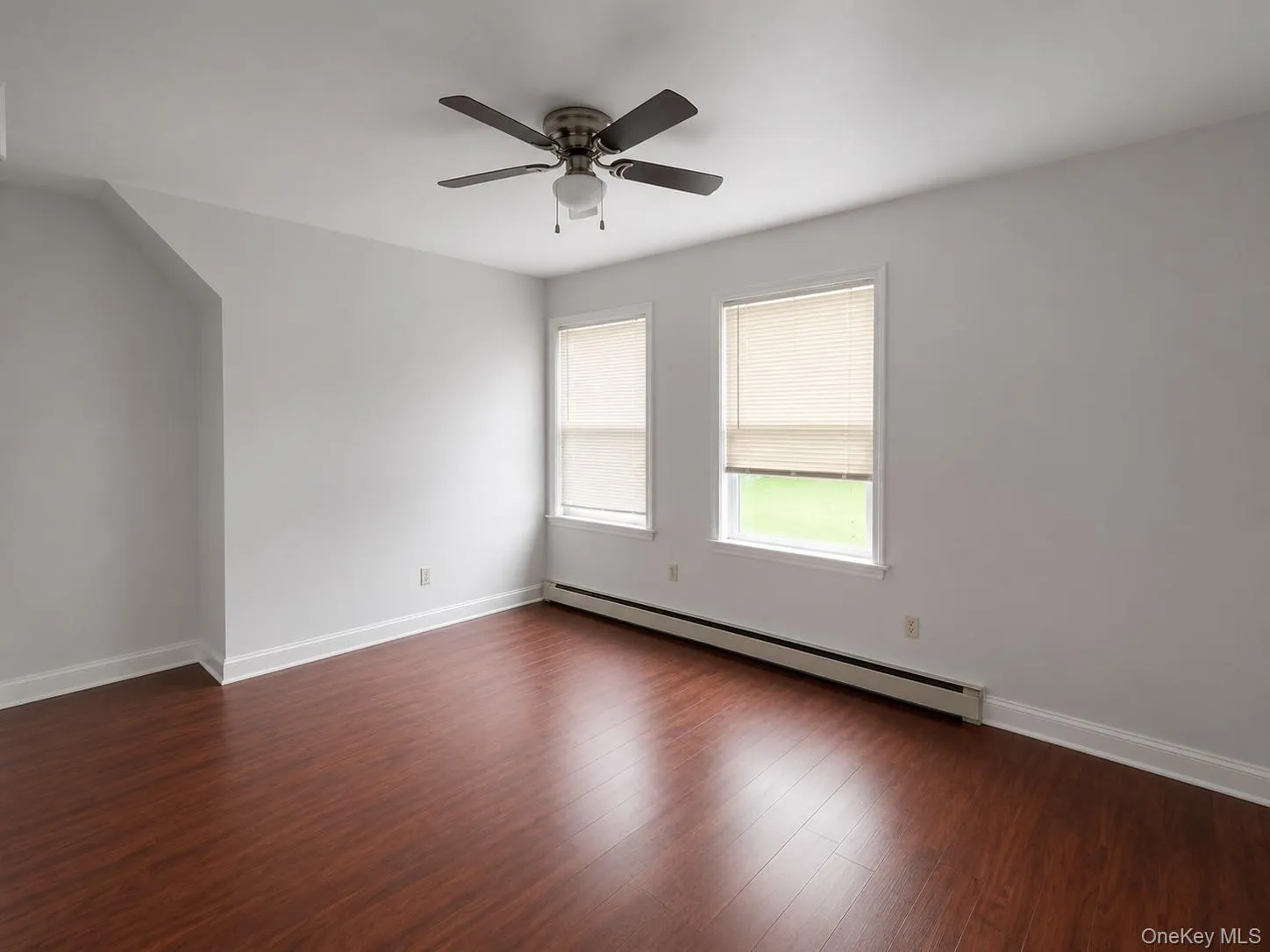 Bright corner room featuring gleaming wood-finish flooring, dual windows with natural light exposure, ceiling fan with integrated lighting, and neutral wall finishes***Photos have been digitally staged to remove clutter*** Bright corner room featuring gleaming wood-finish flooring, dual windows with natural light exposure, ceiling fan with integrated lighting, and neutral wall finishes***Photos have been digitally staged to remove clutter***