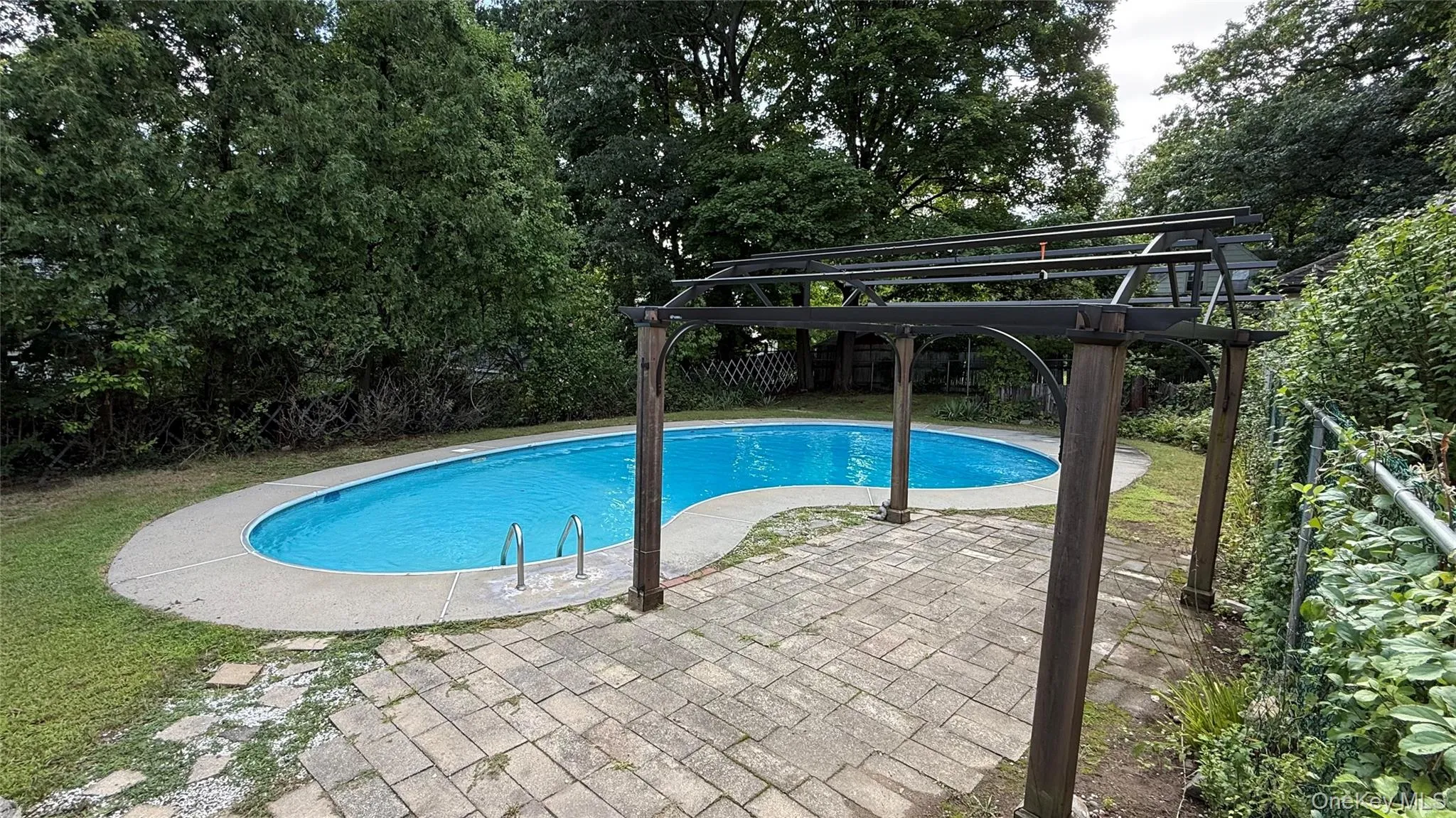 Oval-shaped swimming pool with concrete surround Oval-shaped swimming pool with concrete surround