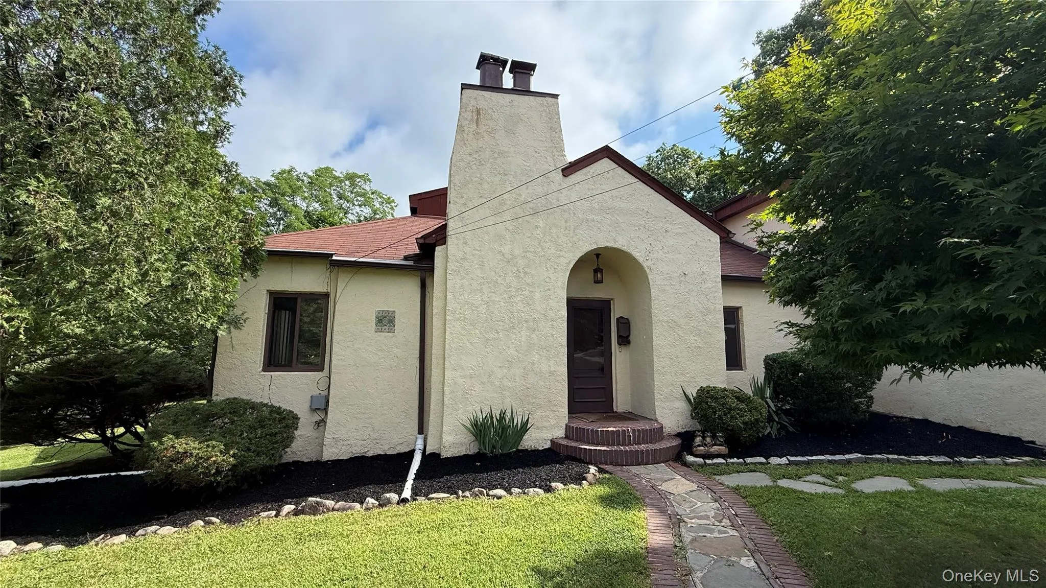 Stucco exterior with a prominent chimney and arched entry Stucco exterior with a prominent chimney and arched entry