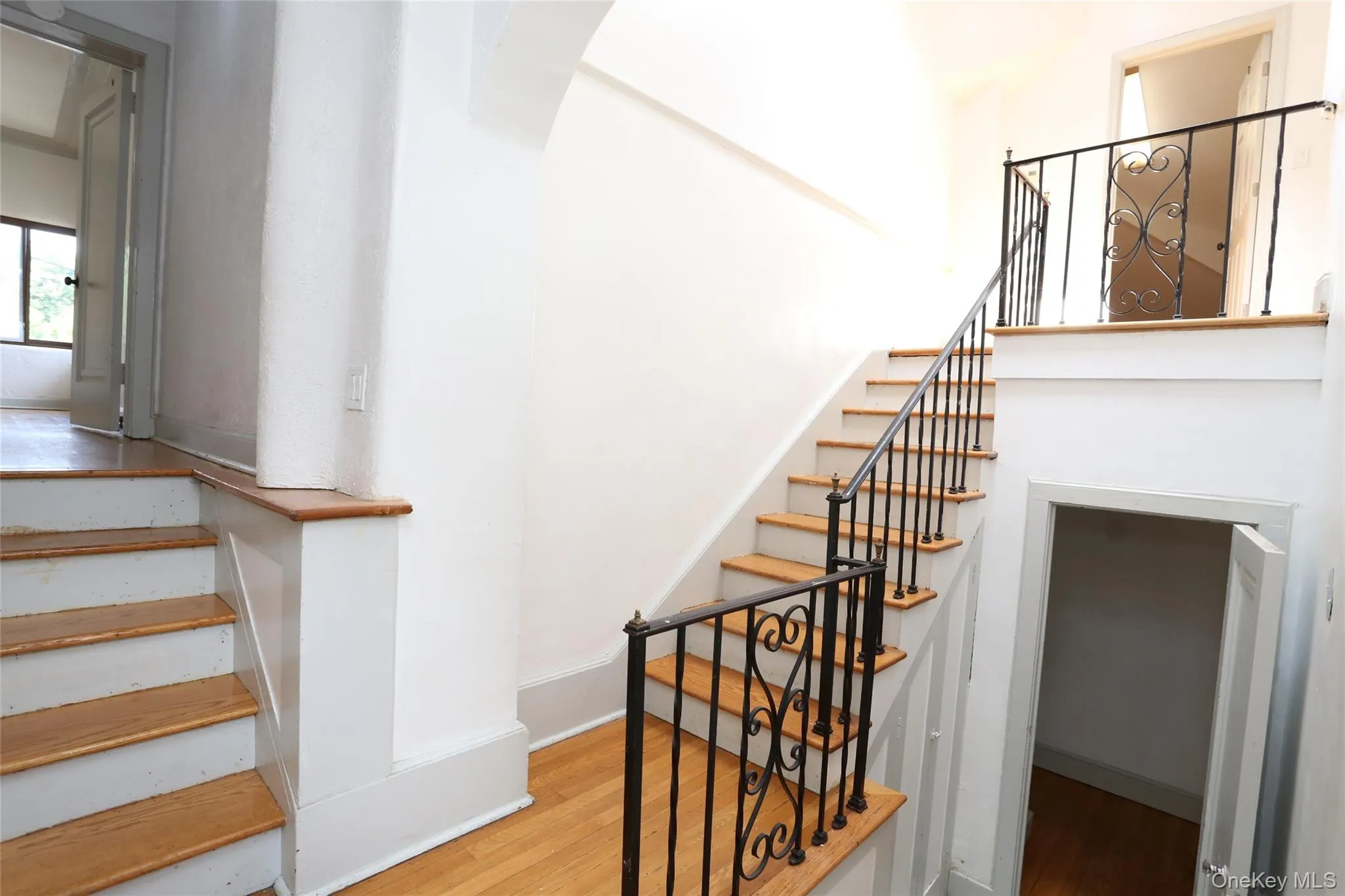 Hardwood flooring throughout, featuring a staircase with wrought iron railings and wood treads Hardwood flooring throughout, featuring a staircase with wrought iron railings and wood treads