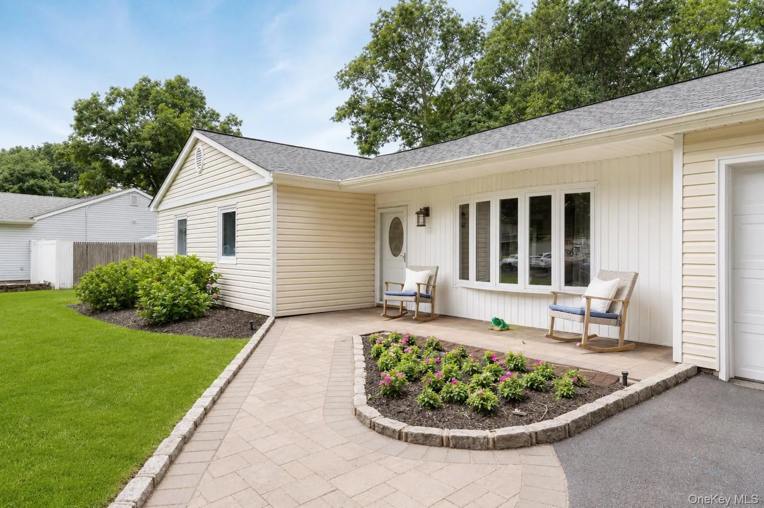 The covered front paver patio and flower bed enhance the curb appeal. Digitally enhanced grass. The covered front paver patio and flower bed enhance the curb appeal. Digitally enhanced grass.