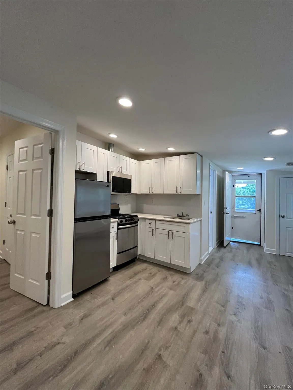 Kitchenette featuring white cabinetry, stainless steel appliances, and a solid surface countertop Kitchenette featuring white cabinetry, stainless steel appliances, and a solid surface countertop