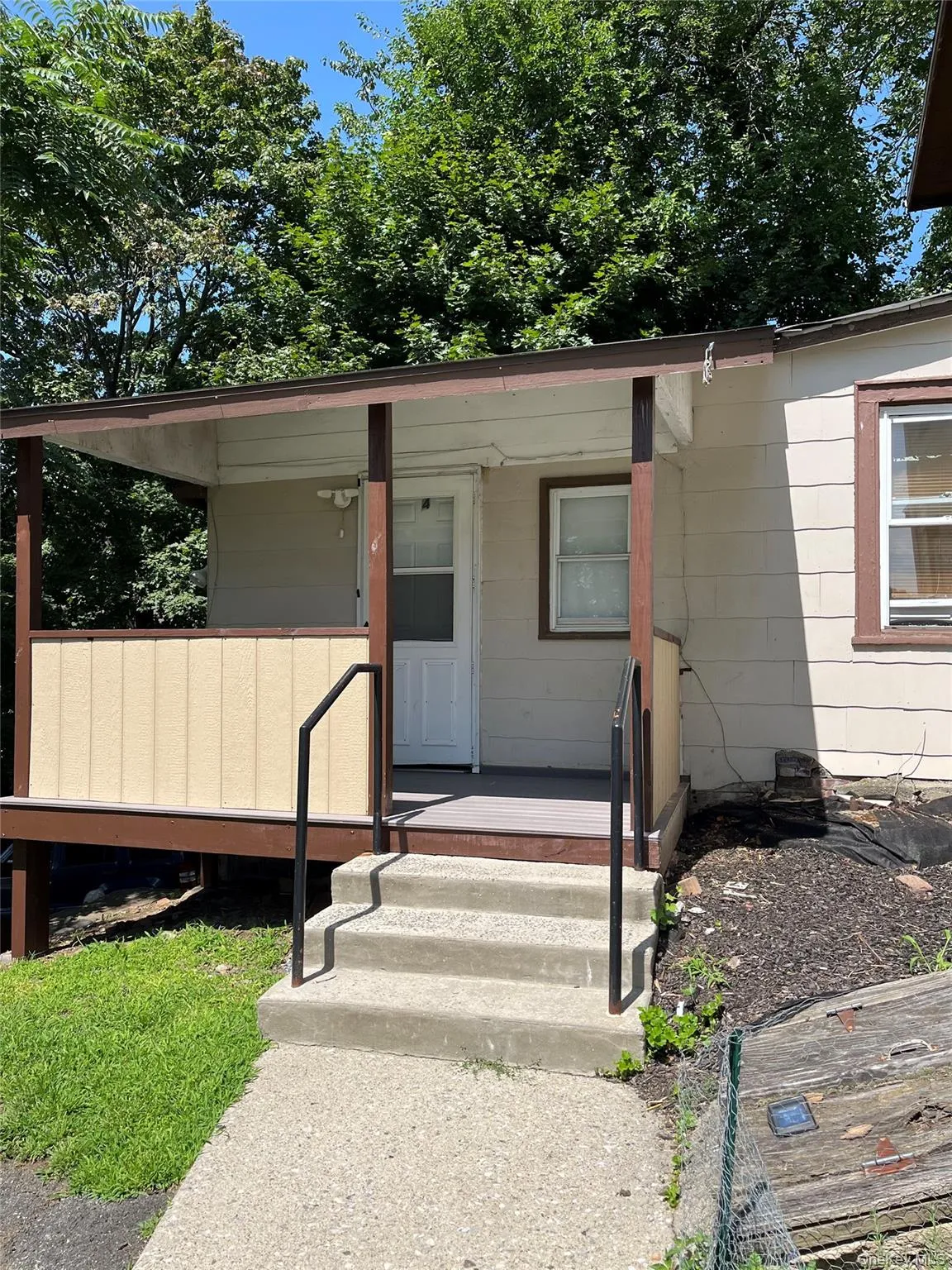 Covered front porch with dark wood-finish columns and railing Covered front porch with dark wood-finish columns and railing