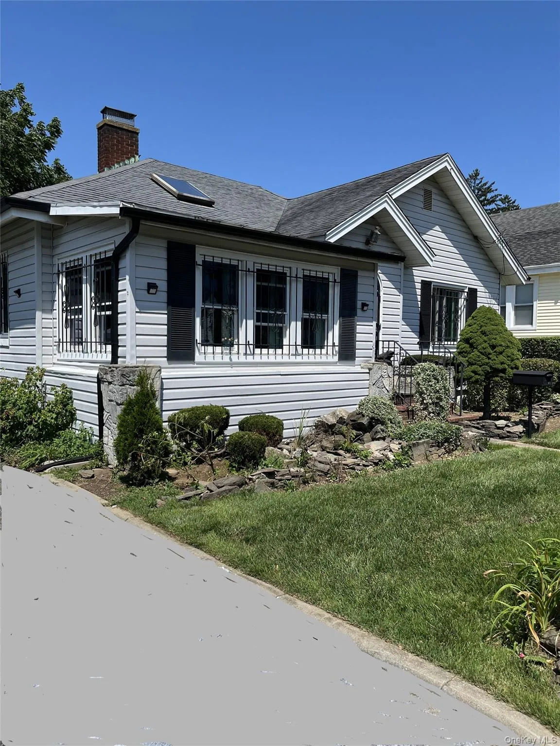 Light-colored siding exterior with shingled roof, featuring a visible skylight Light-colored siding exterior with shingled roof, featuring a visible skylight