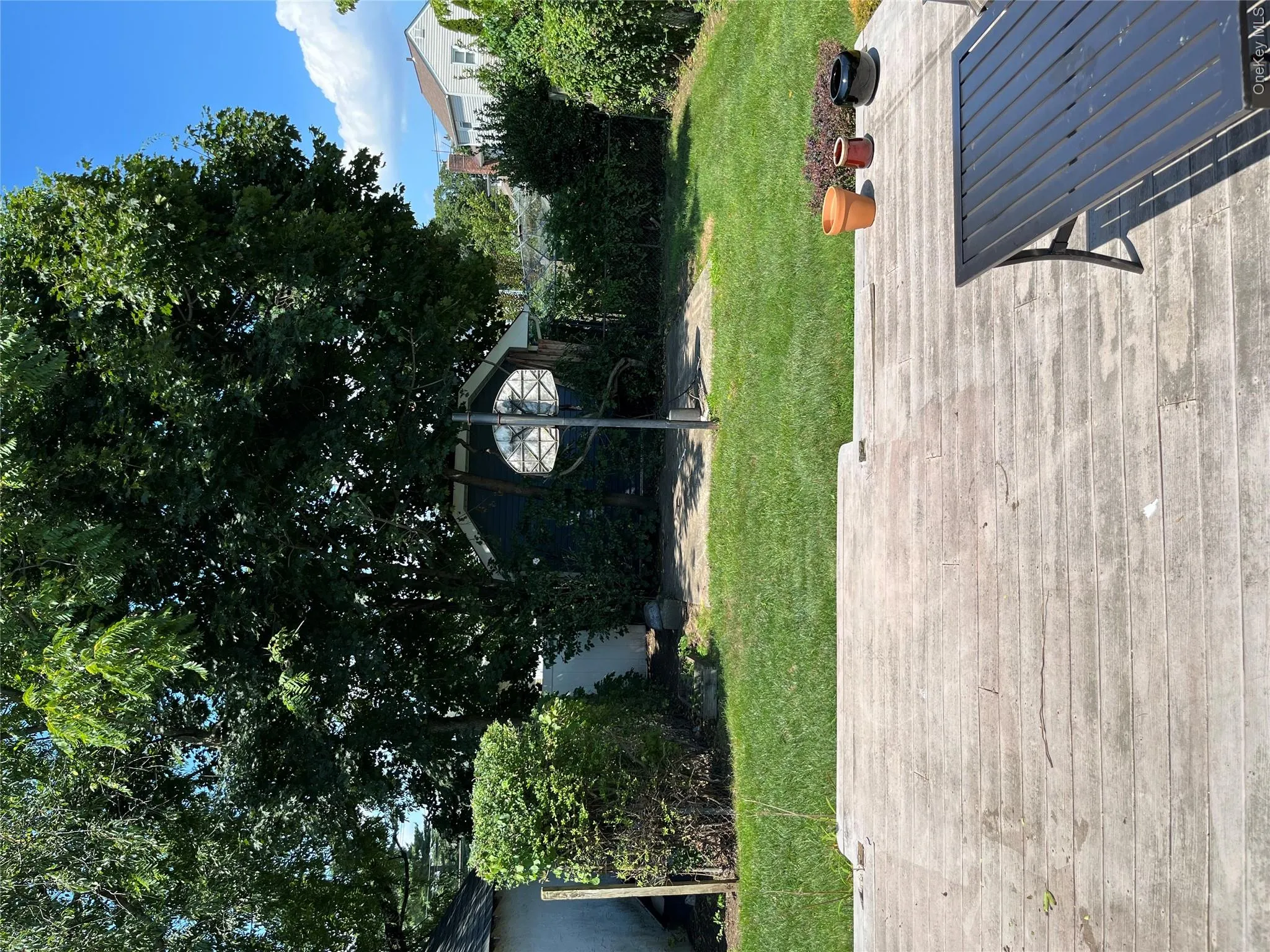 Expansive backyard featuring a concrete patio, a manicured lawn, and mature trees Expansive backyard featuring a concrete patio, a manicured lawn, and mature trees