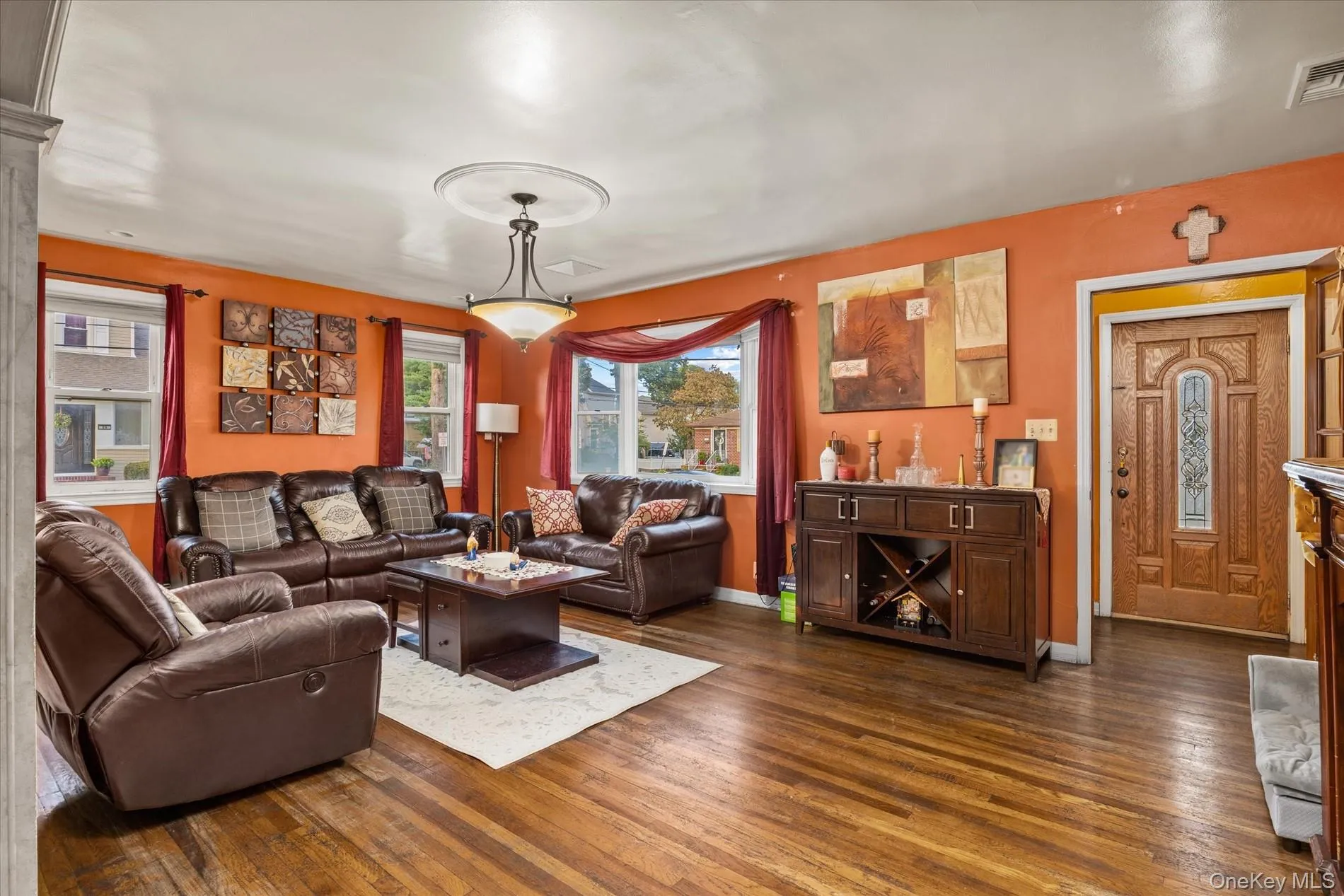 Hardwood flooring, decorative front entry door with leaded glass insert, multiple windows with natural light, ceiling medallion with attached lighting fixture, and a built-in wood-finish credenza Hardwood flooring, decorative front entry door with leaded glass insert, multiple windows with natural light, ceiling medallion with attached lighting fixture, and a built-in wood-finish credenza